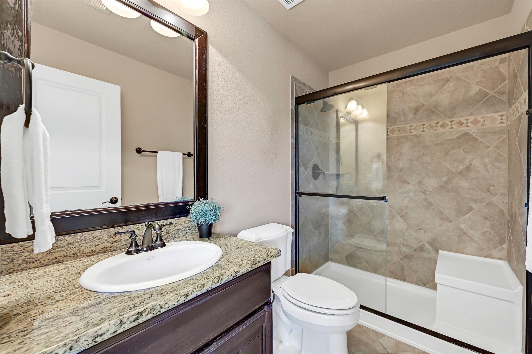 The en suite bathroom is finished with granite countertops, dark wood cabinetry, oil-rubbed bronze fixtures, and a tiled tub/shower combination that complements the homes upscale finishes. This bathroom is also accessible from the nearby game room.