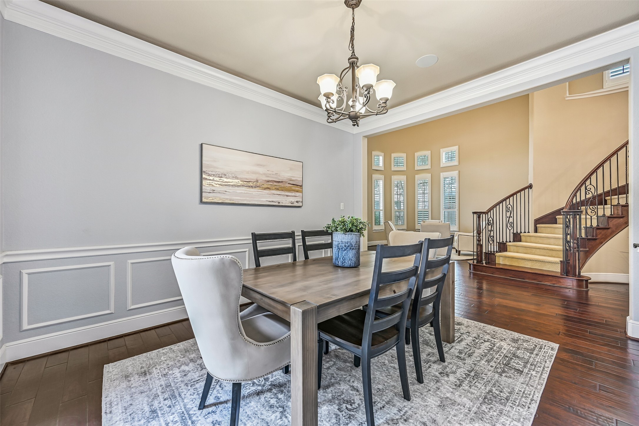 The formal dining room is beautifully finished with triple crown molding, chair rail and picture frame molding, elegant uplighting, and a sculpted iron chandelier suspended beneath the tray ceiling. French doors open to a private courtyard, creating a charming backdrop for both everyday dining and special gatherings.
