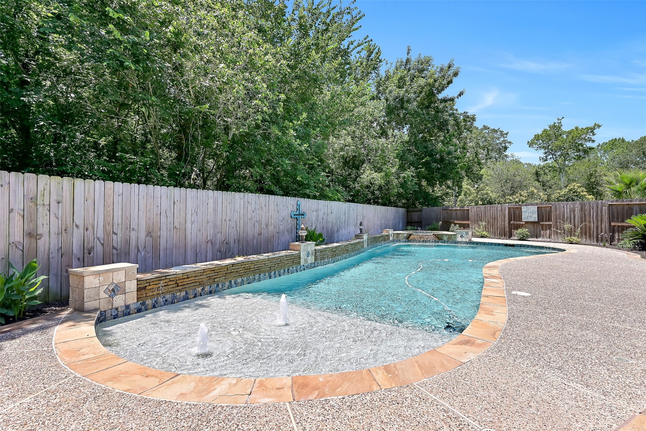 Designed for entertaining, the custom pool features a spacious 9x12 tanning ledge with bubblers and an umbrella holder, upgraded wet-edge premium pebble plaster, and a dramatic stacked flagstone weeping wall with water features.