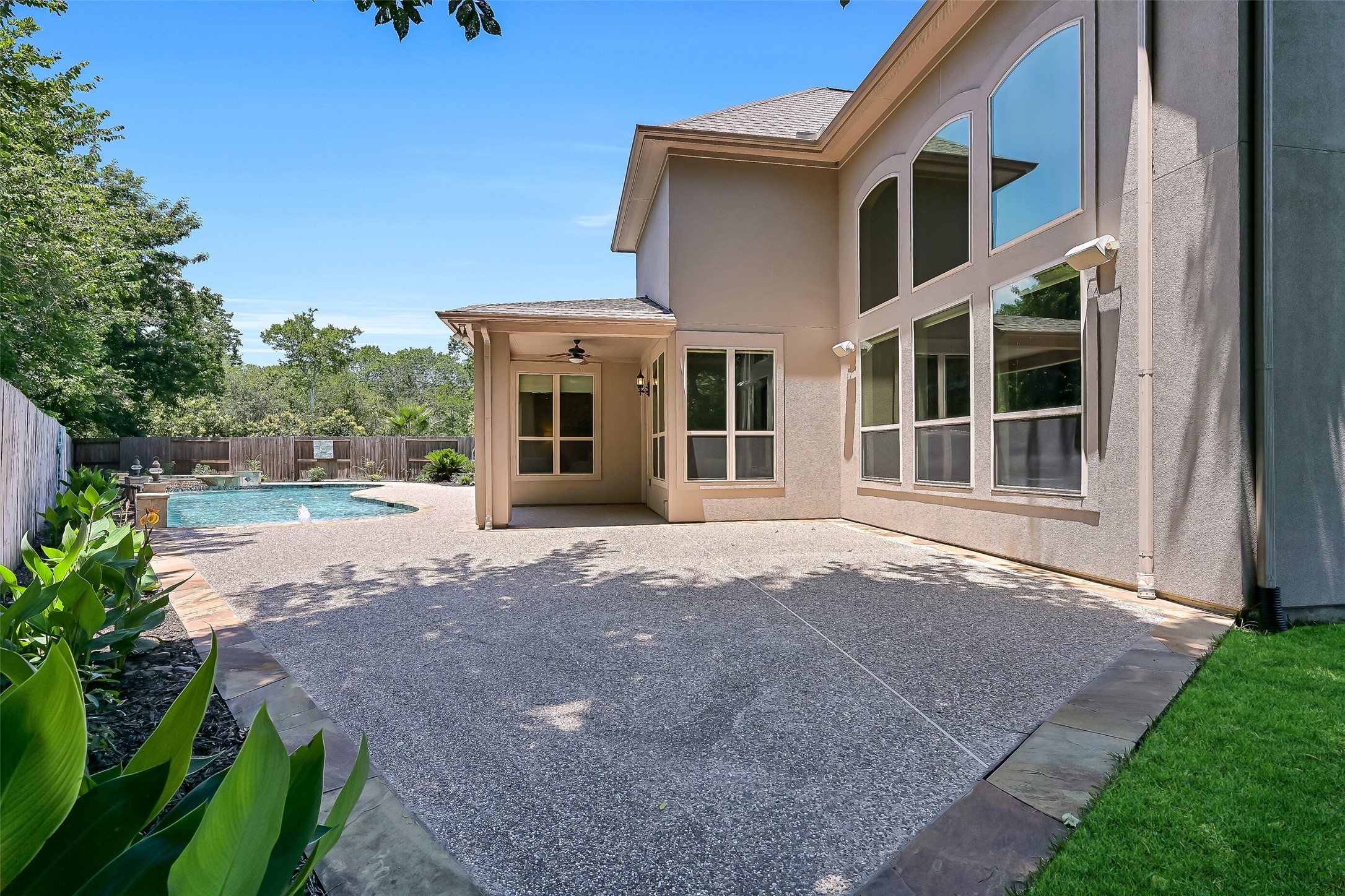 The backyard offers extensive patio space for lounging, dining, and entertaining, with the covered patio positioned perfectly to enjoy views of the pool and surrounding greenery.
