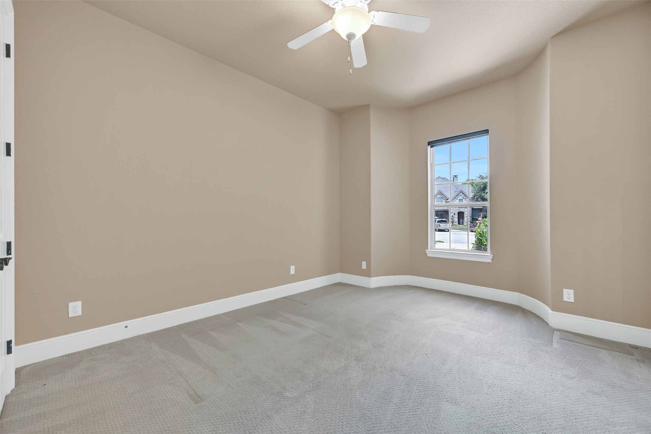 Privately situated on the first floor, this secondary guest suite offers plush sculpted carpet, soft natural light, a lighted ceiling fan, and a quiet front-facing location that works beautifully for overnight guests, multigenerational living, or a private home office.