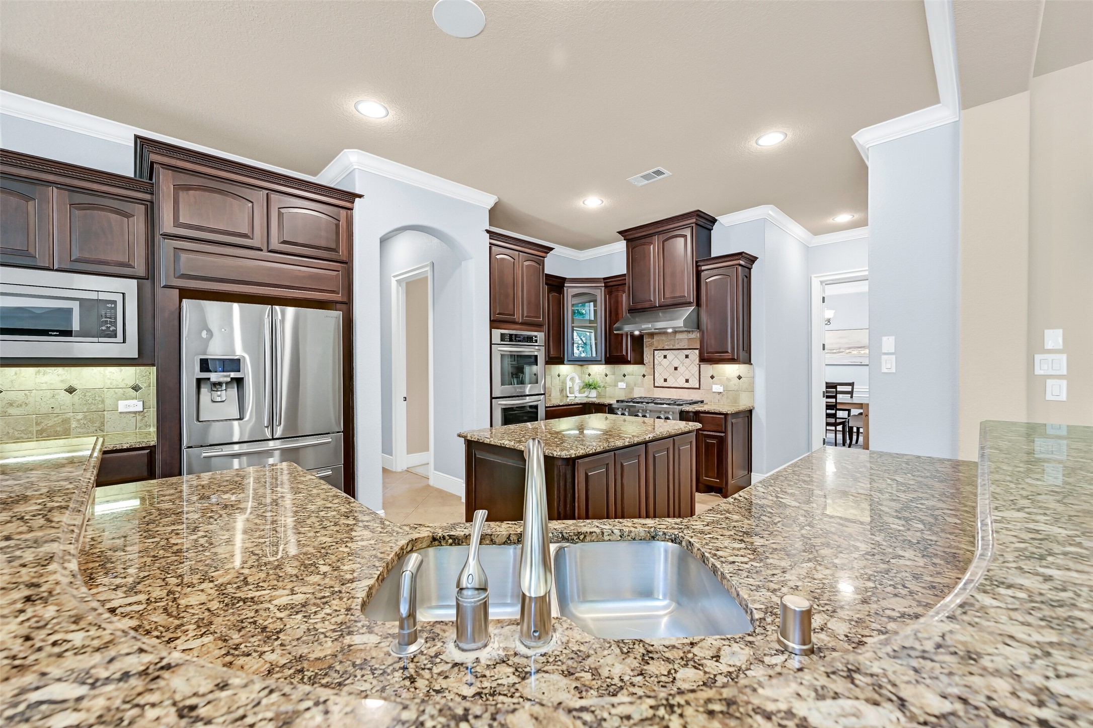 From the sink, you can overlook both the family room and breakfast area while preparing meals, making the kitchen feel connected to the entire home. Granite counters, a deep basin sink, and extensive prep space surround the central island for effortless everyday living and entertaining.