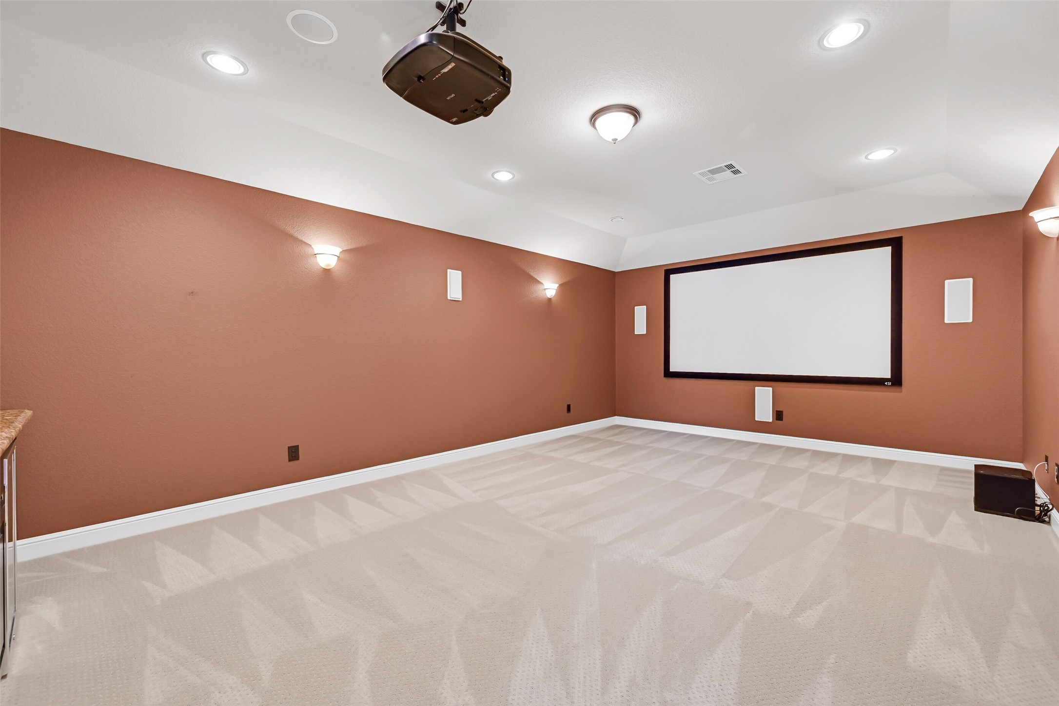 Designed for the ultimate cinematic experience, the dedicated media room features dimmable sconce lighting, recessed lighting, an existing projector and screen setup, built-in surround sound speakers, and ample space for theater-style seating.