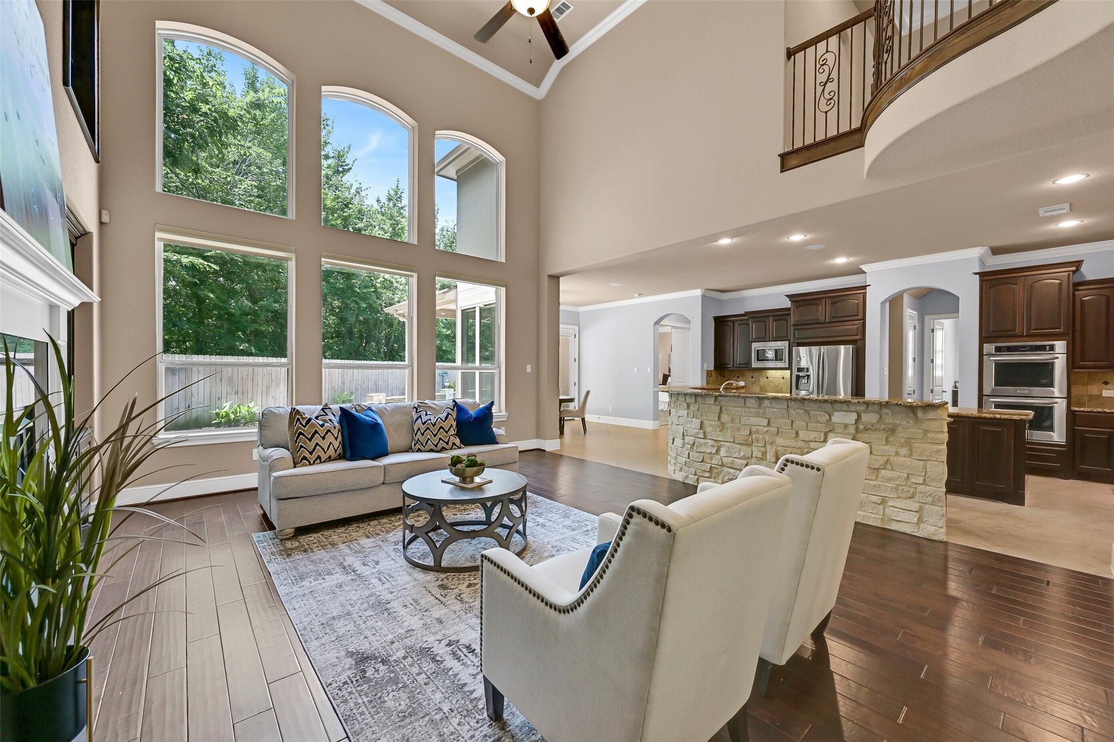 Open to the kitchen and breakfast room, this expansive family room was clearly designed for gathering with built-in speakers, recessed lighting, a ceiling fan, and generous seating areas all positioned beneath the dramatic second-story ceiling and overlooking the pool area.
