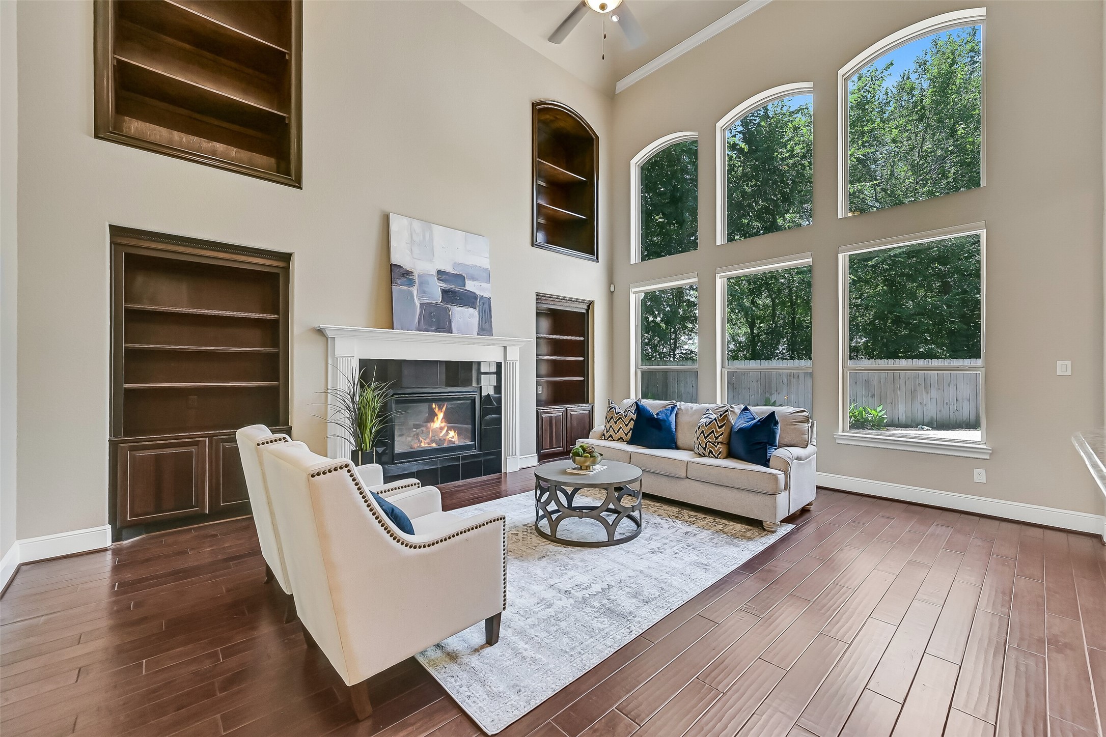Another view of the family room highlights the incredible natural light and soaring vertical scale of the space, with oversized windows framing peaceful backyard views and creating a seamless connection between the indoor living areas and outdoor entertaining spaces beyond.