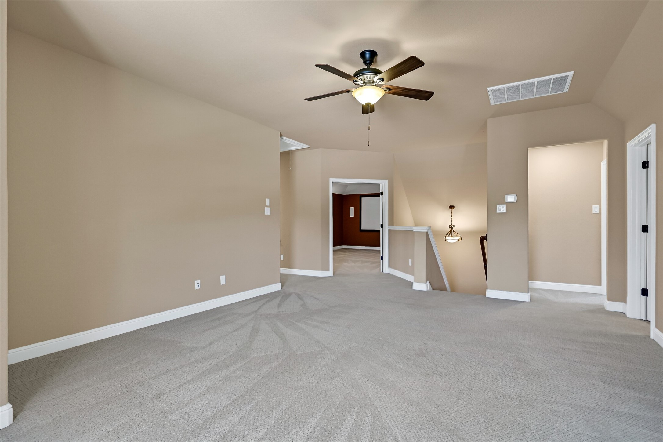 Another angle highlights the expansive scale of the game room and its open connection to the upper level, creating the perfect gathering space for entertaining or everyday relaxation. Here, you'll catch a glimpse of the rear staircase and the double door entrance to the media room.