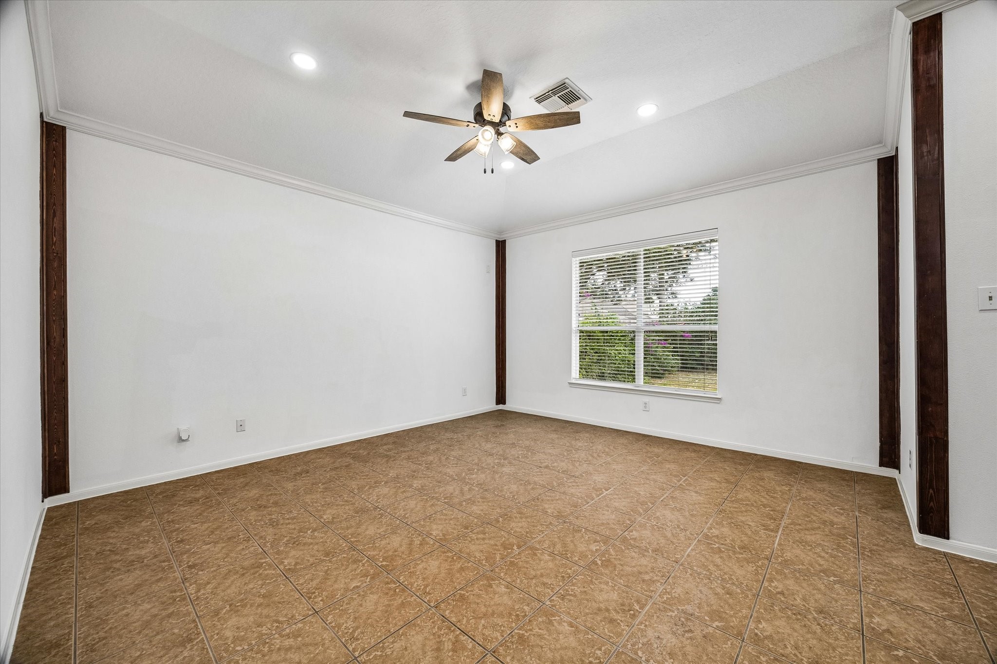 Spacious room featuring elegant tile flooring, a modern ceiling fan, and ample natural light through a large window, perfect for versatile living.