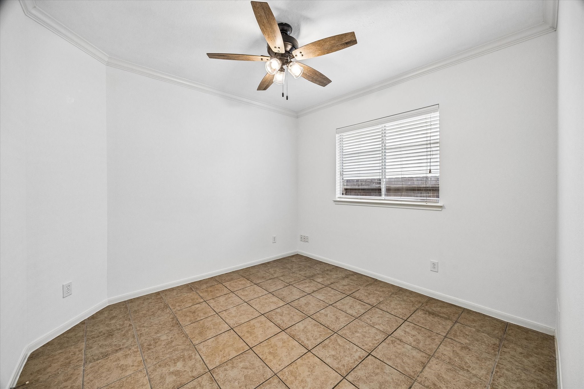 Bright and inviting room featuring neutral tile flooring, a ceiling fan, and ample natural light from a well-placed window. Perfect for versatile use.