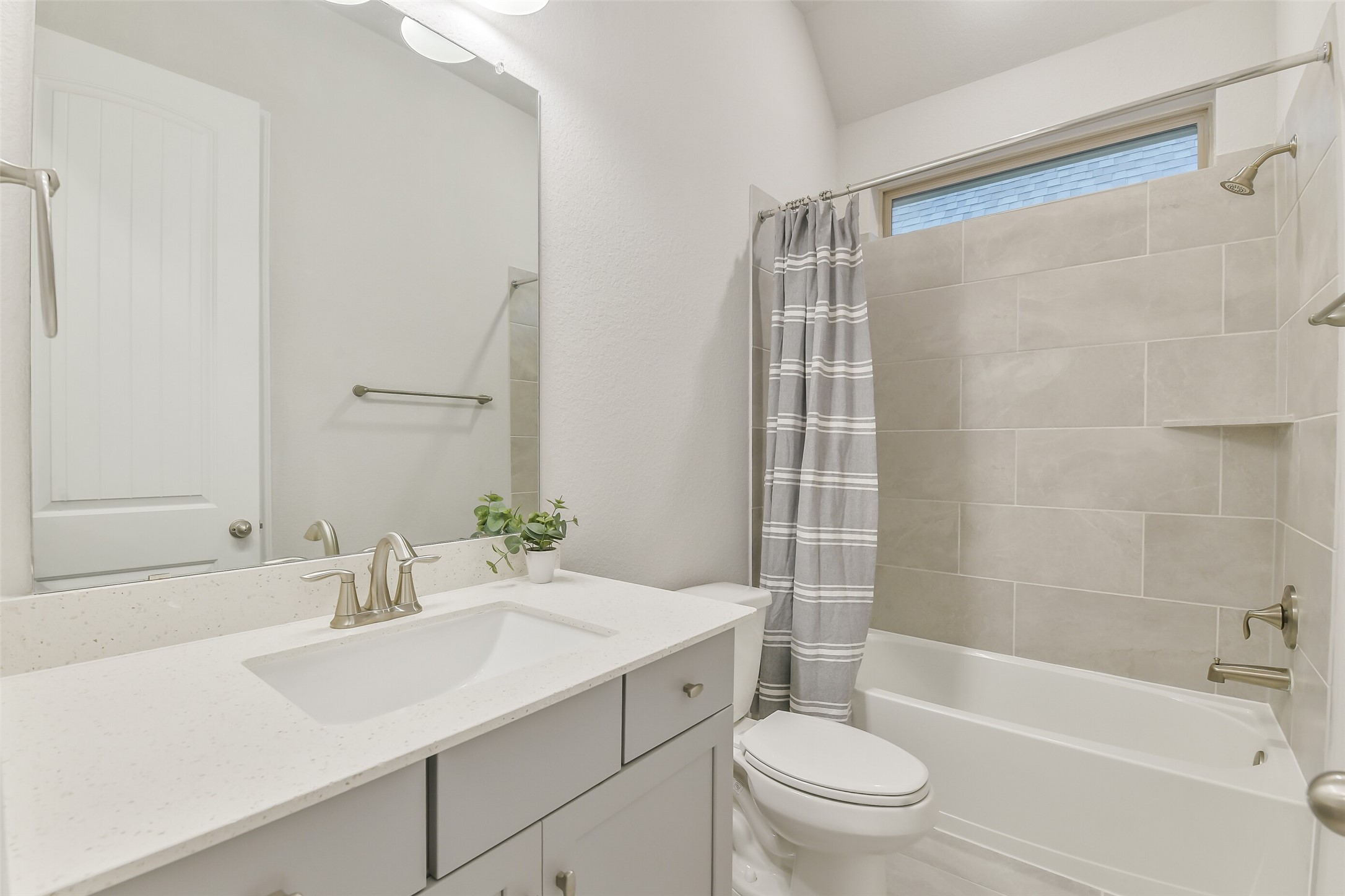 This bathroom features a shower and tub combo and a sink with plenty of counterspace.