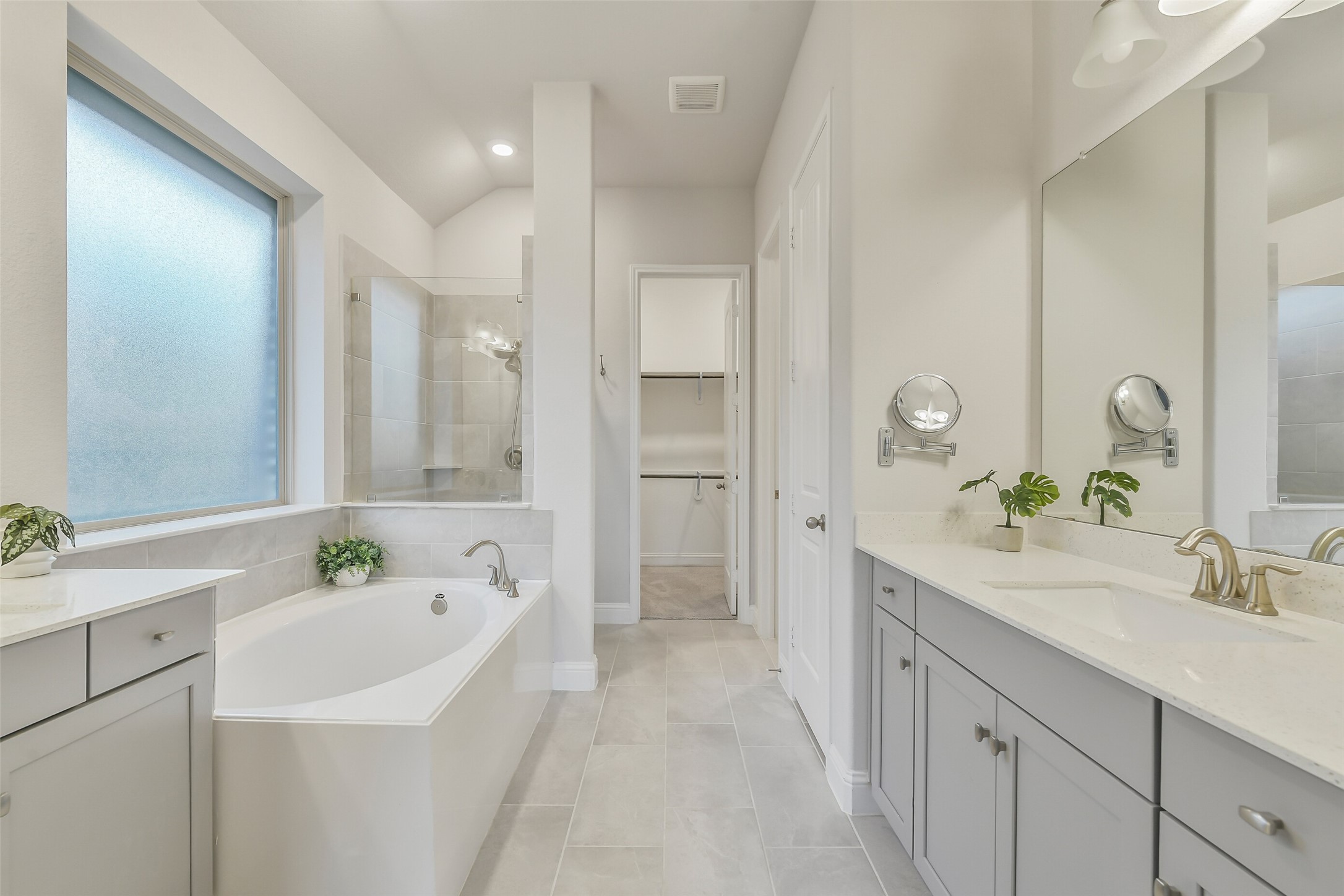 The gorgeous primary bathroom features bright lighting, cabinetry, a large walk in shower and soaking tub.