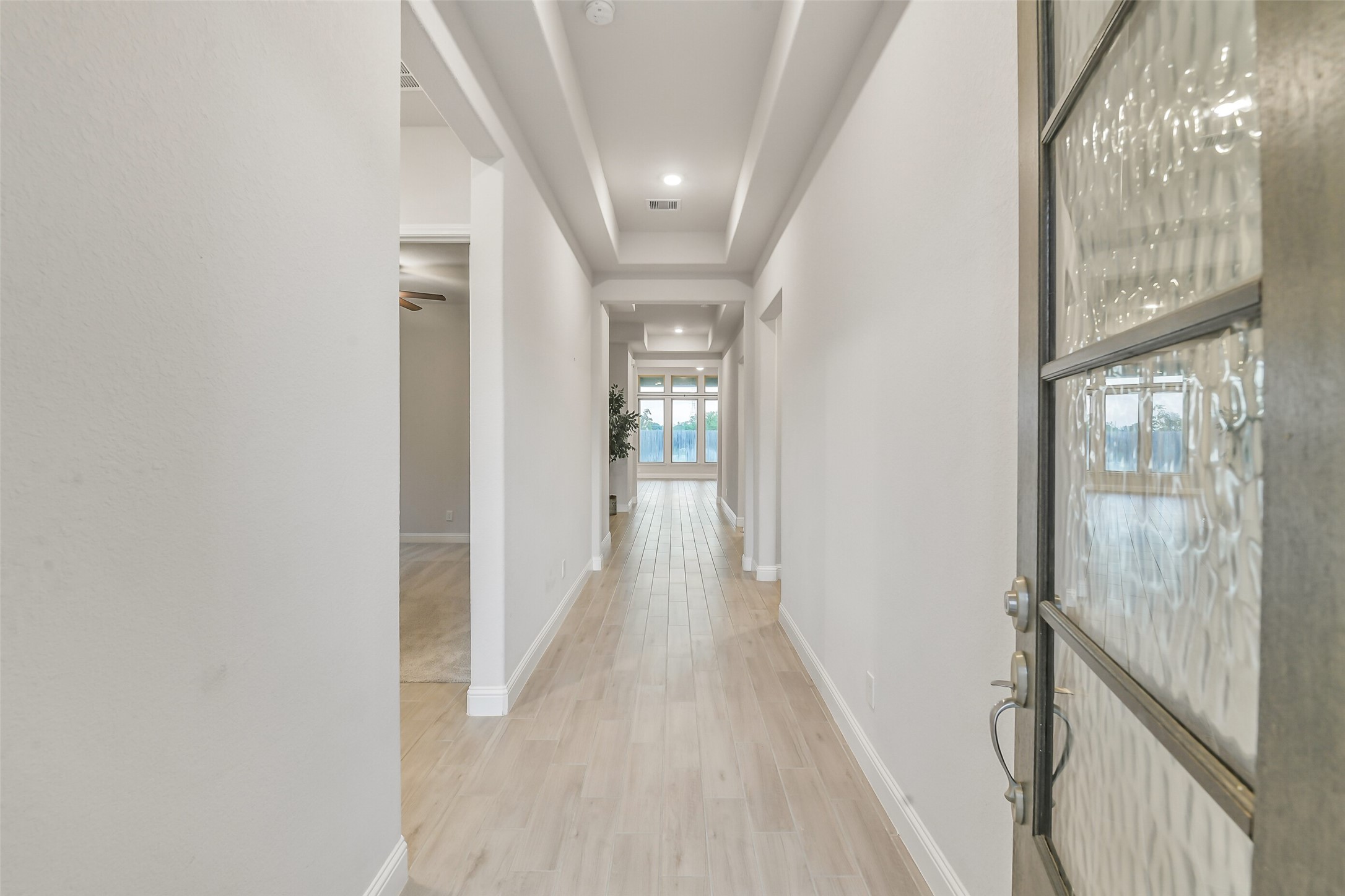 A wood and glass door open to a beautiful hallway entry.