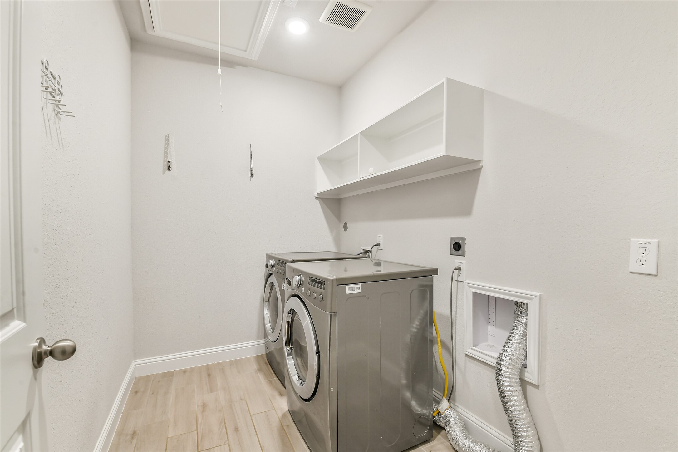 This laundry room has plenty of room for a full sized washer and dryer as well as storage.