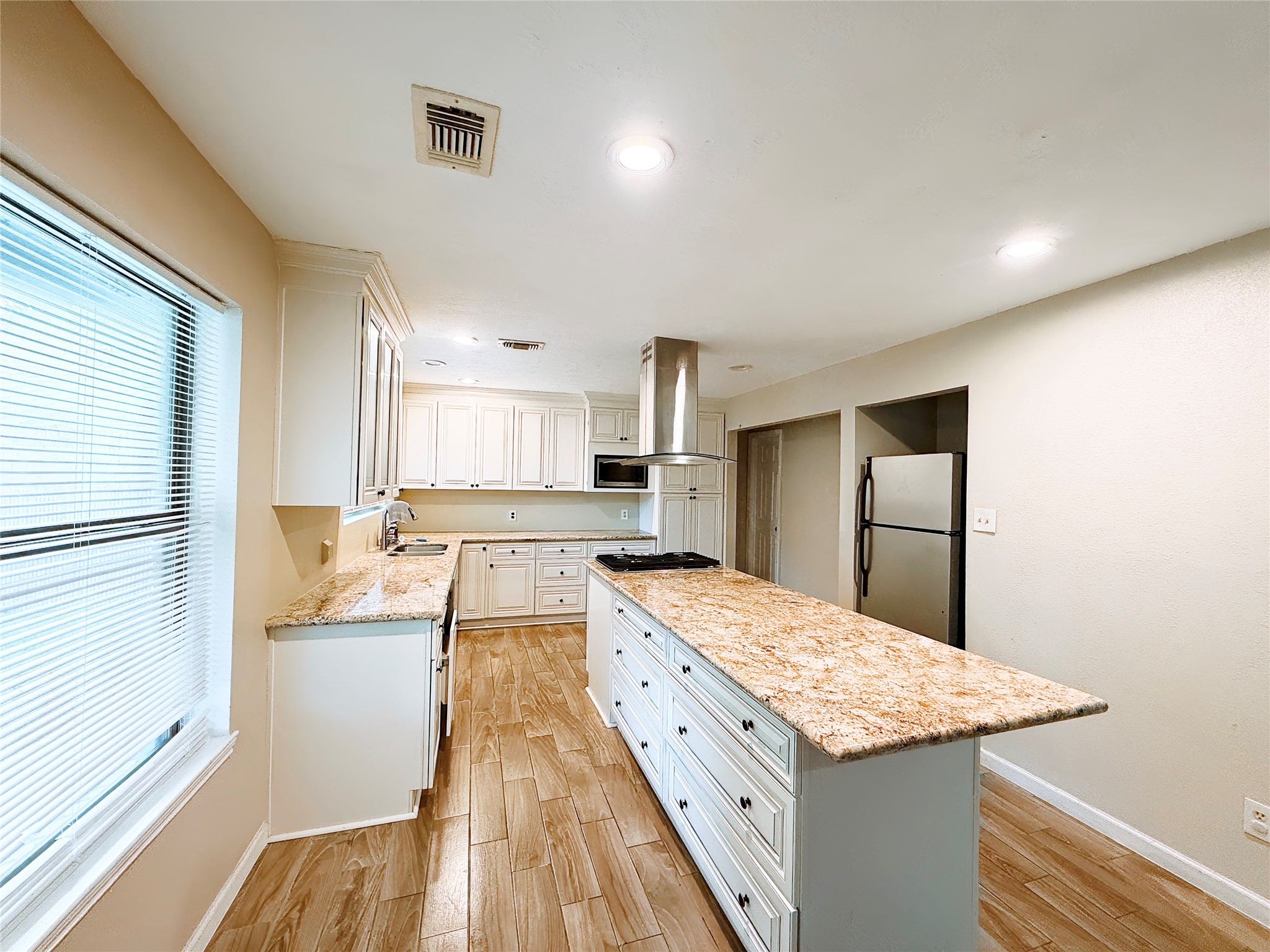 Spacious kitchen featuring sleek granite countertops, modern stainless steel appliances, and warm wood flooring, perfect for culinary enthusiasts.