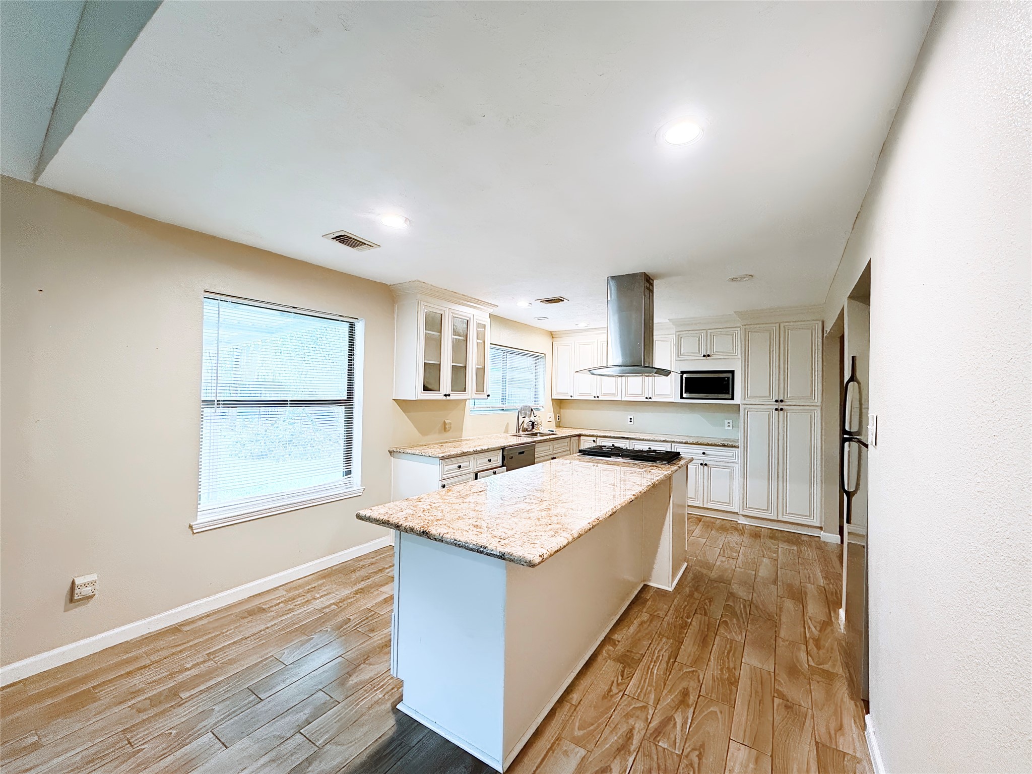 Spacious kitchen with a large granite island, modern stainless steel appliances, and elegant cabinetry, all illuminated by ample natural light.