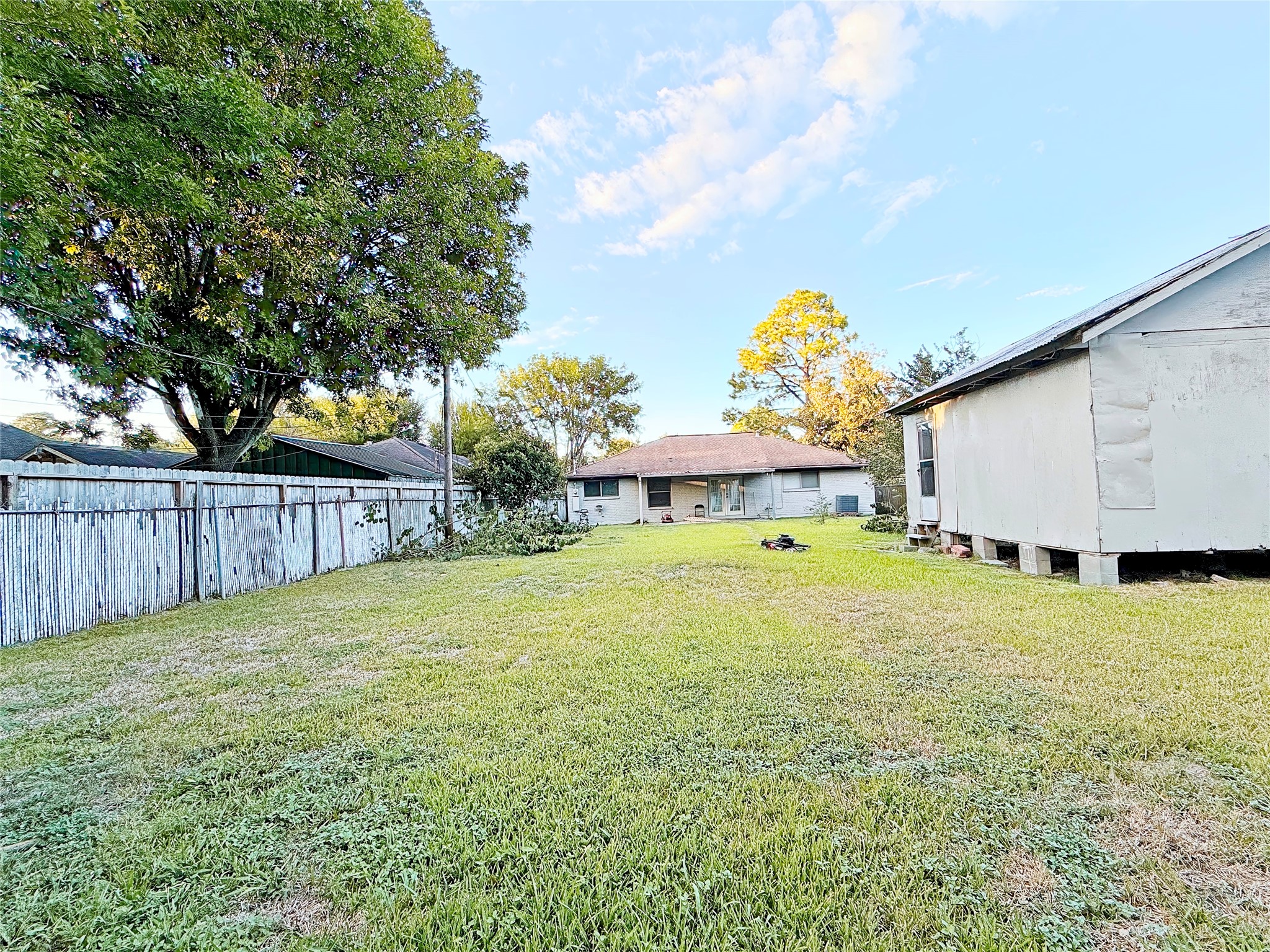 Expansive backyard with lush grass, mature trees, and a charming ranch-style home offering ample outdoor space and privacy.