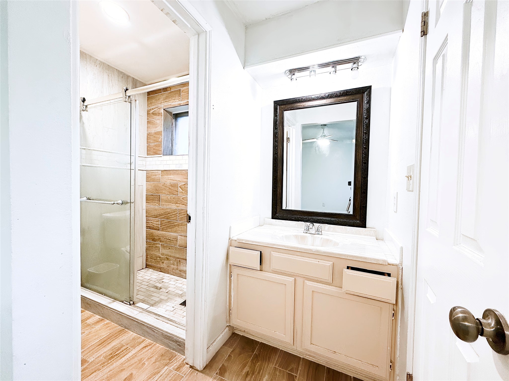Charming bathroom featuring a sleek glass-enclosed shower with elegant tilework, complemented by a spacious vanity with a large framed mirror.