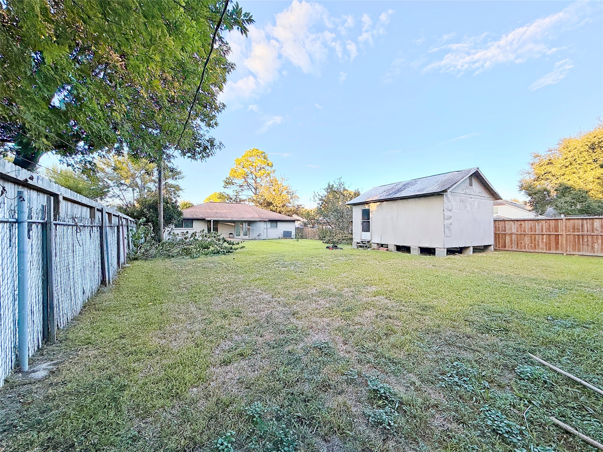 Expansive backyard featuring a spacious lawn, a detached storage shed, and mature trees offering ample shade and privacy.