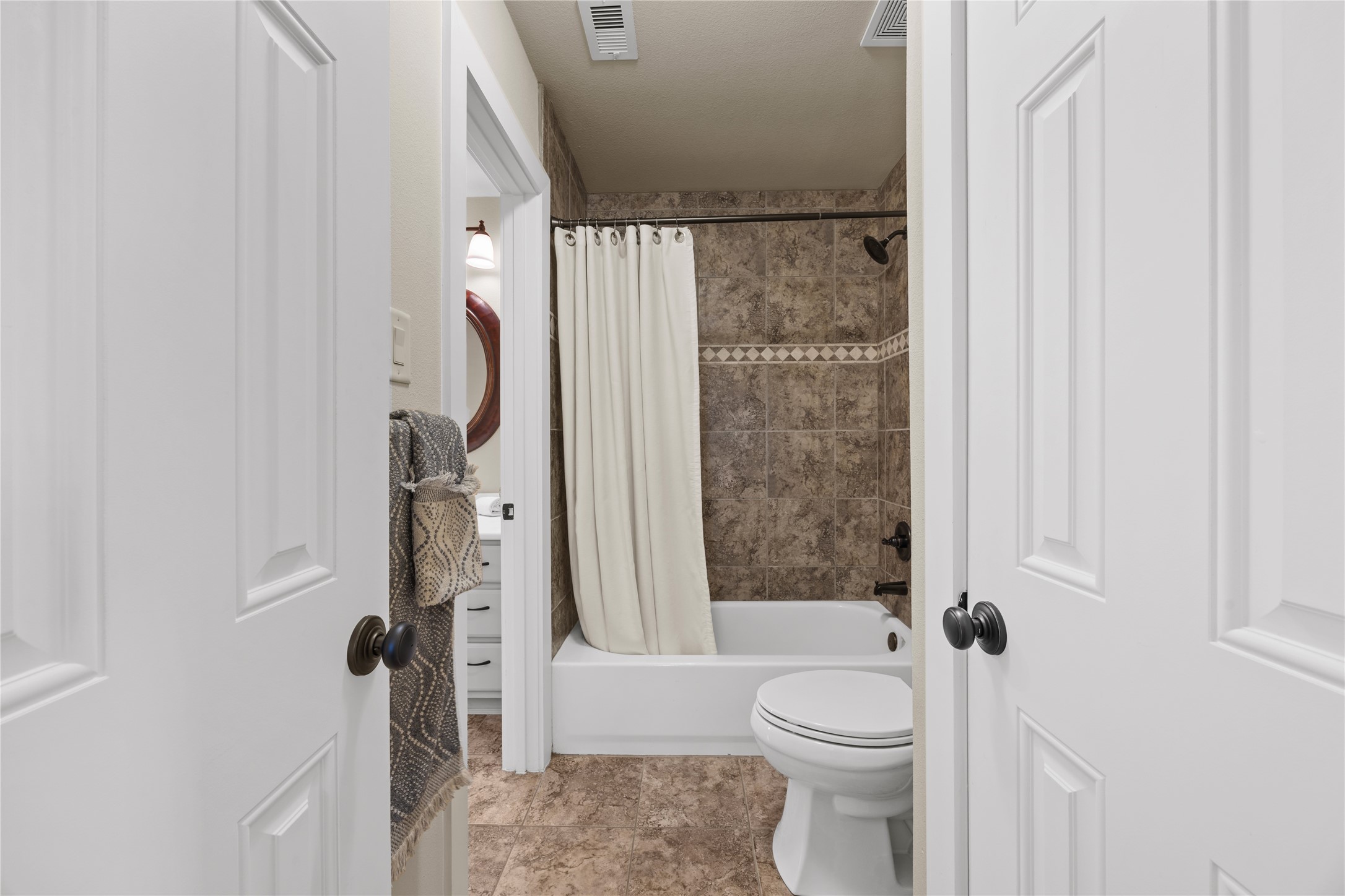 Convenient upstairs bathroom featuring a tub/shower combination with decorative tile surround and neutral finishes.