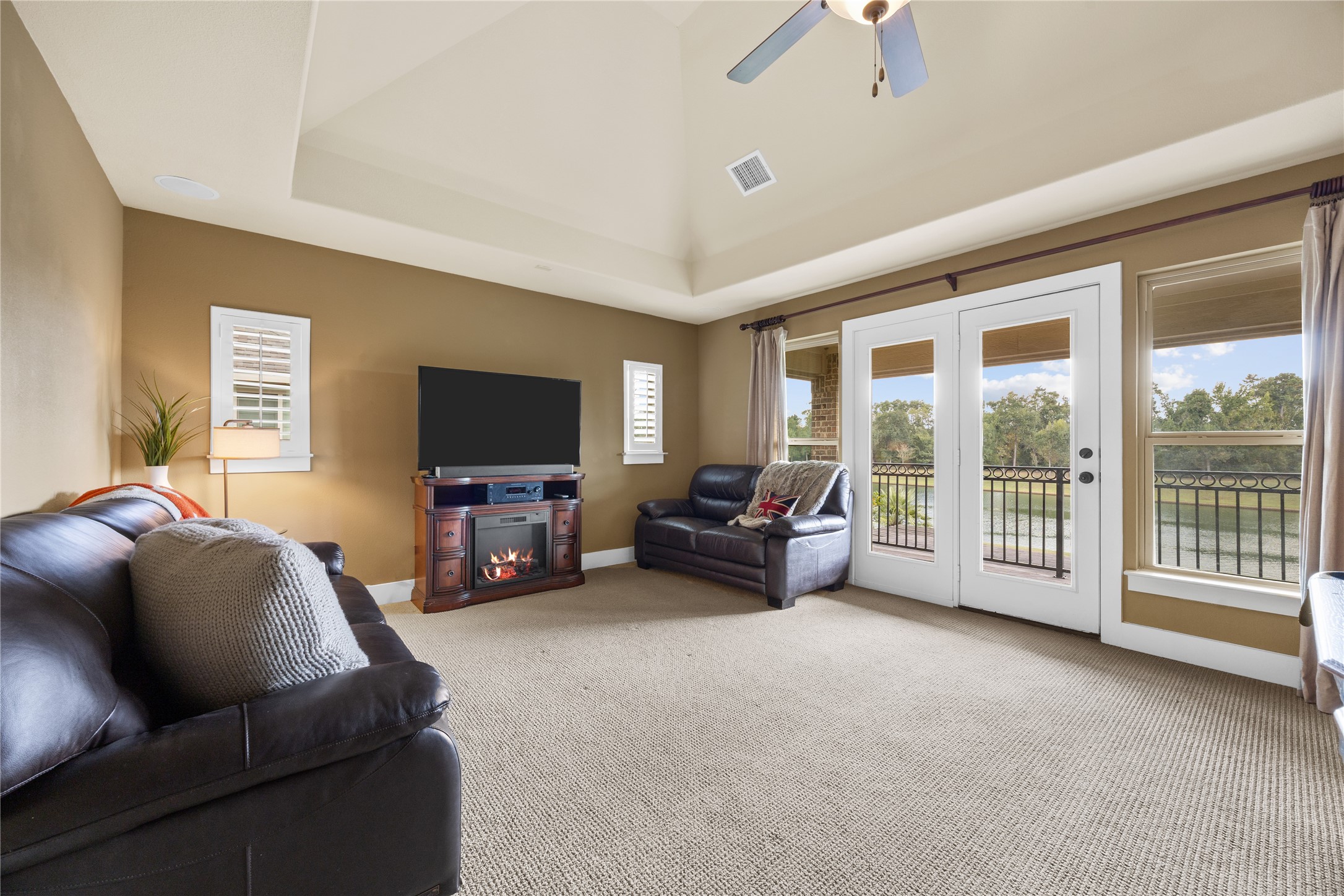 A room with a view! The upstairs game room features a soaring ceiling and French doors opening to a covered balcony overlooking the water.