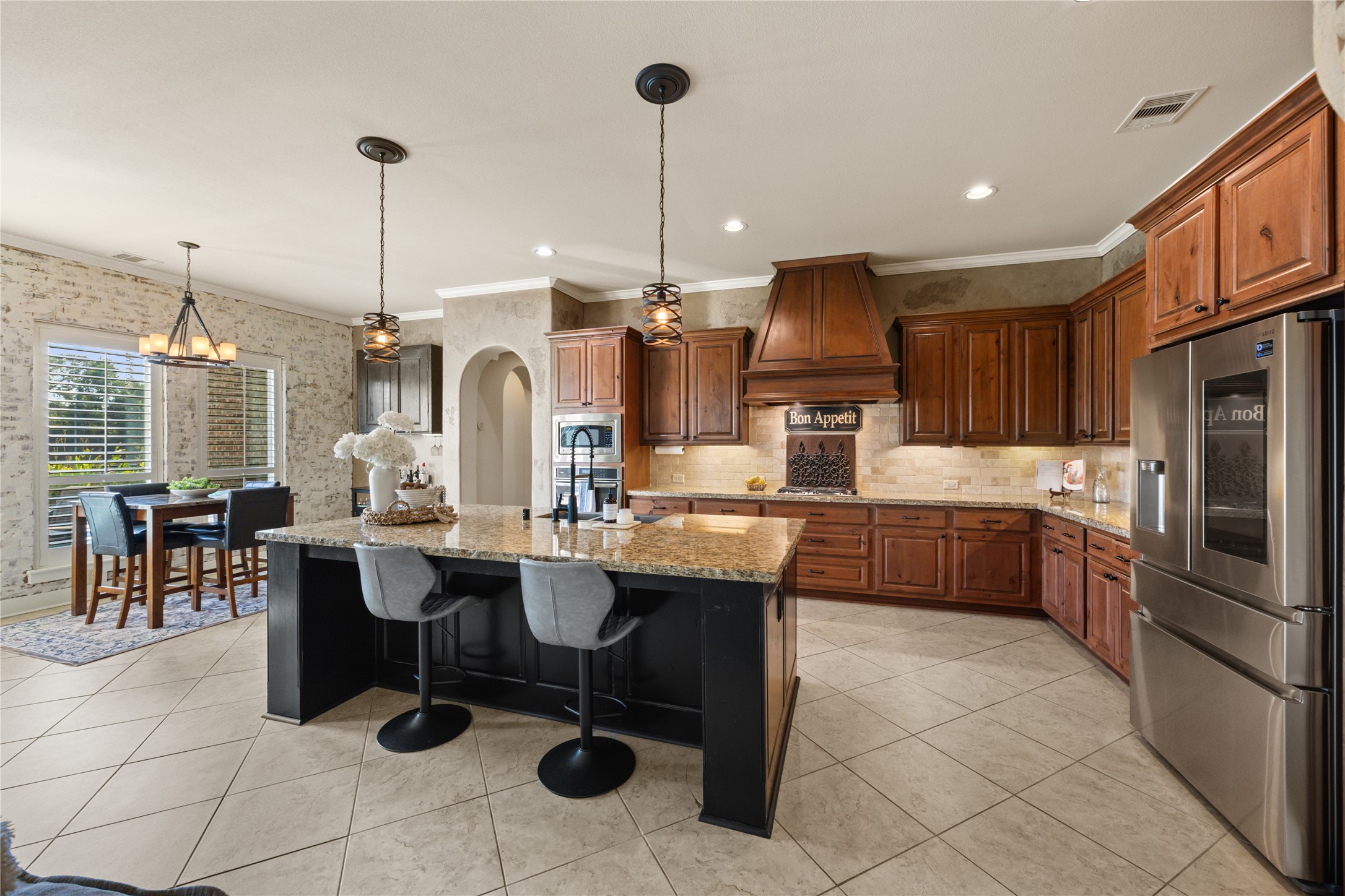 Beautifully designed kitchen opens to the breakfast area, featuring a large center island, rich wood cabinetry, granite countertops, and abundant natural light.