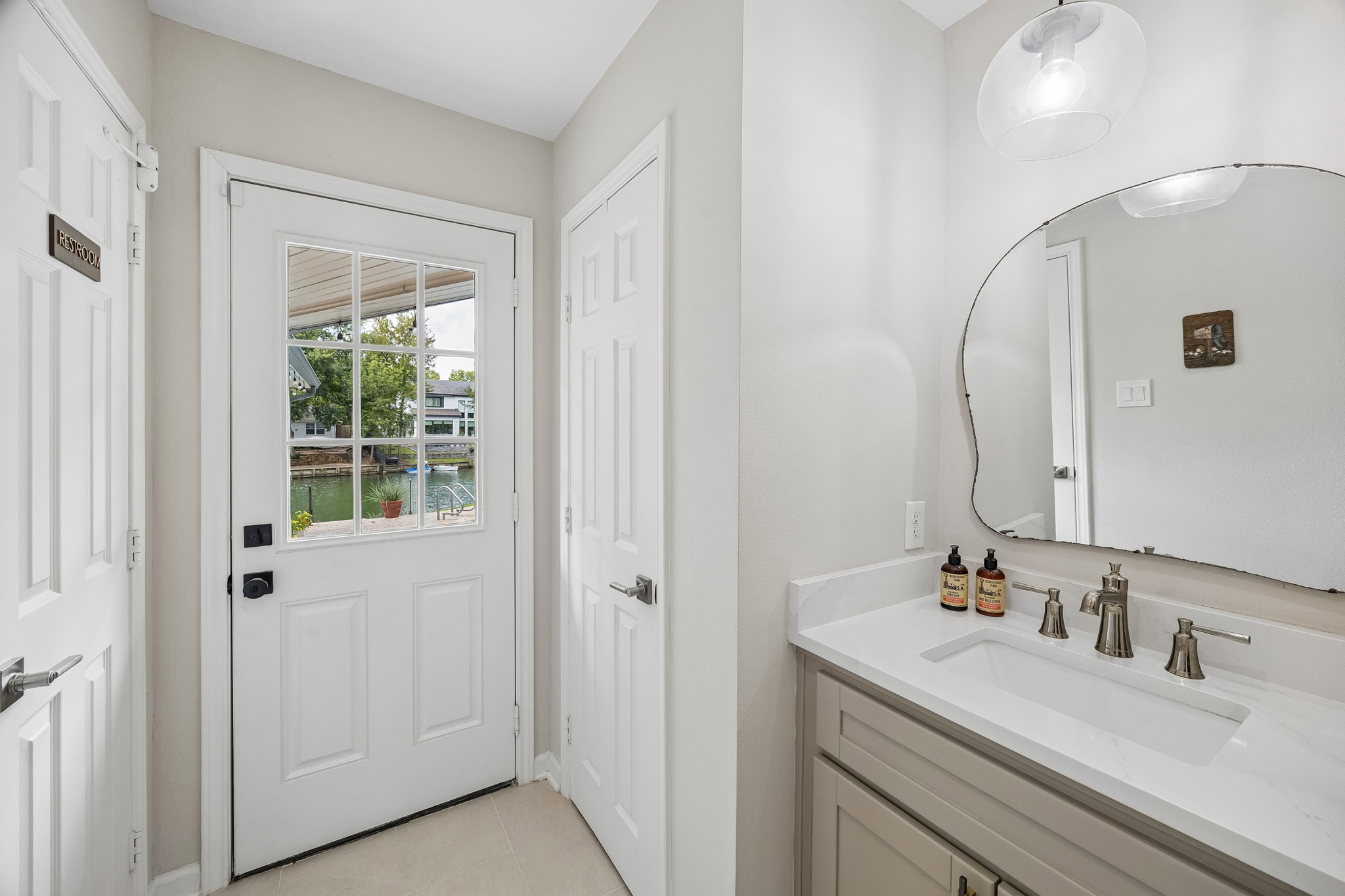 Convenient hallway featuring a storage closet, the half bath, and direct access to the backyard.