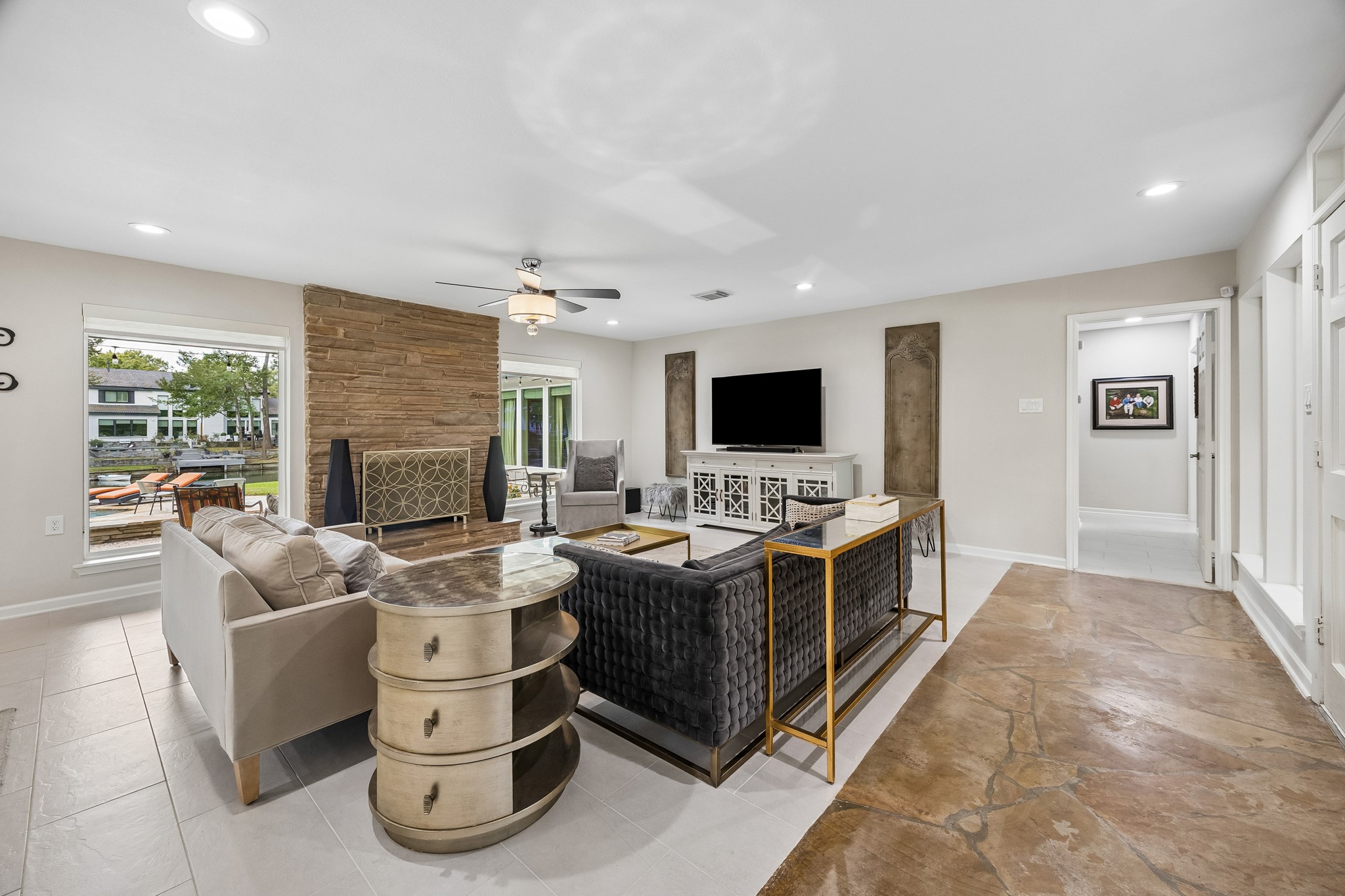 The windows flanking the fireplace provide lovely views of the pool and lake. To the right of the entry, a hallway leads toward the bedrooms, keeping the sleeping space private and quiet. The tile flooring continues down the hall. The windows flanking the fireplace provide lovely views of the pool and lake. To the right of the entry, a hallway leads toward the bedrooms, keeping the sleeping space private and quiet. The tile flooring continues down the hall.