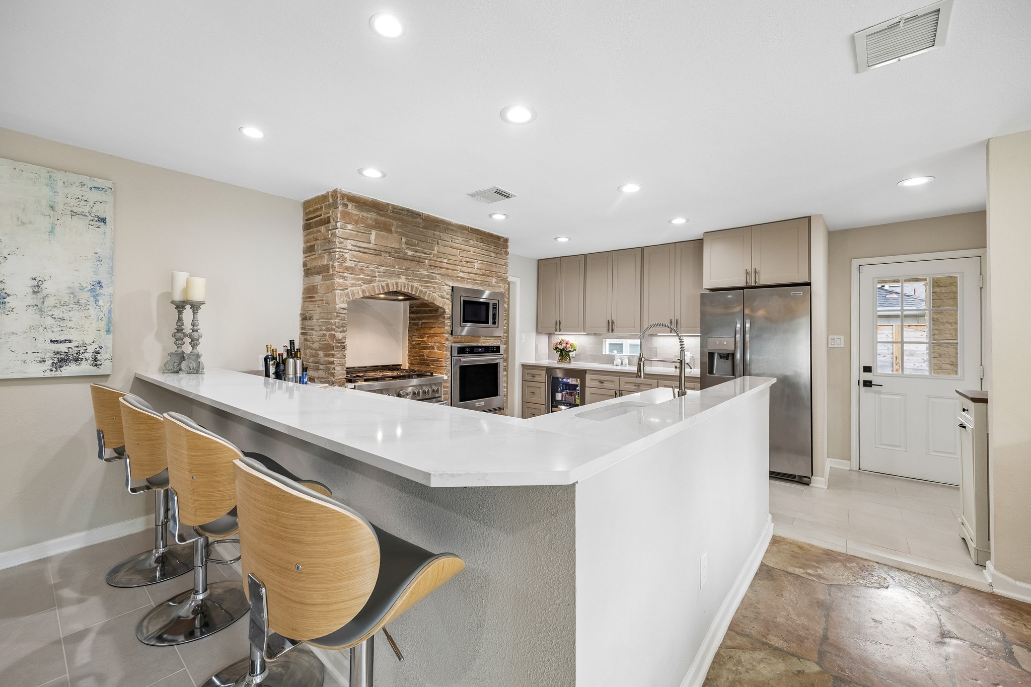 Neutral painted cabinetry spans the back wall of the kitchen, offering abundant storage, while the built-in wine refrigerator adds convenience for entertaining.
