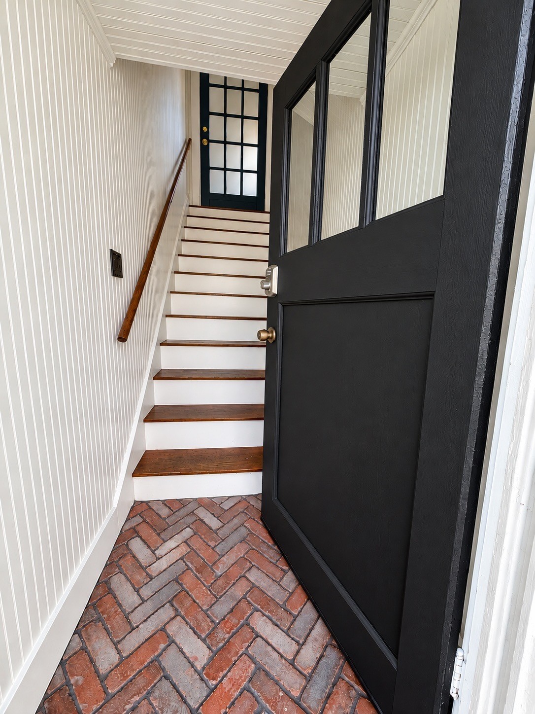 Fully enclosed private entry staircase with classic wood treads, beadboard detailing, and a dedicated exterior entrance.