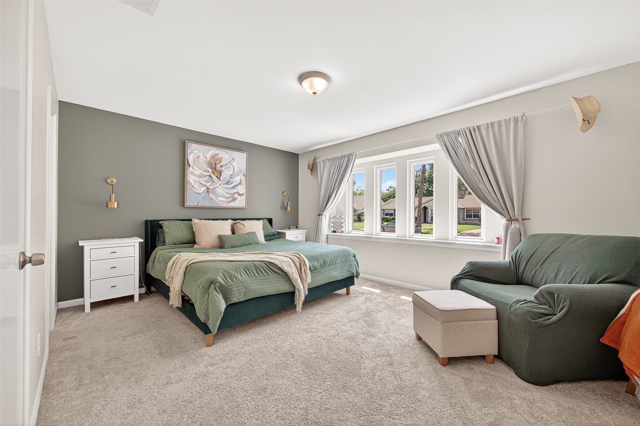 This spacious primary retreat features a cozy carpeted floor, incredible windows with plenty of natural light, and a calming color palette. Ideal for relaxation and comfort.