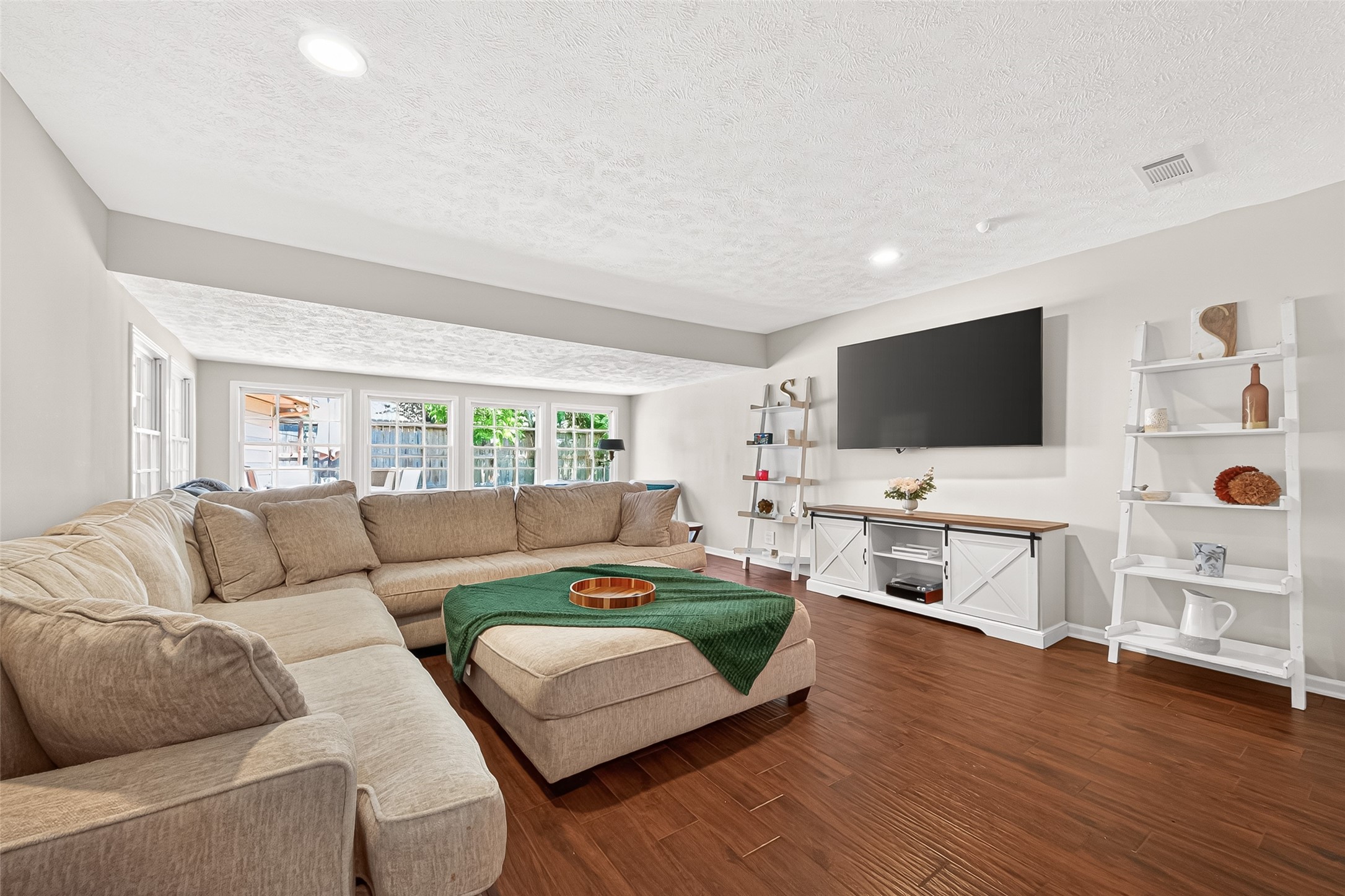 Spacious family room featuring a stunning wall of windows that fills the space with abundant natural light and offers an open, airy feel ideal for relaxing or gathering with family and friends.