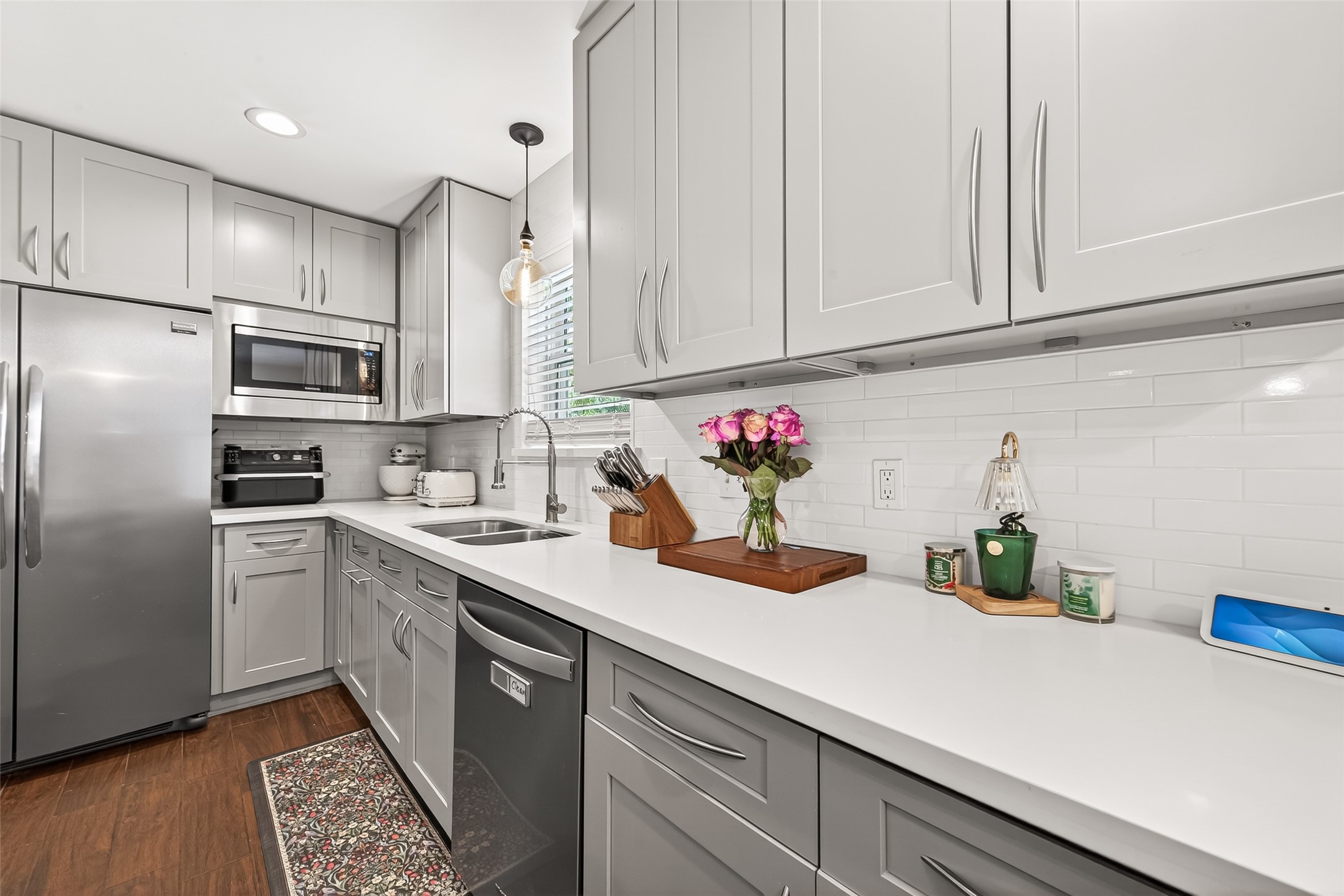 This kitchen features sleek gray cabinetry, stainless steel appliances, and a bright white subway tile backsplash. The space is modern and well-lit, with ample counter space and a clean, contemporary design.