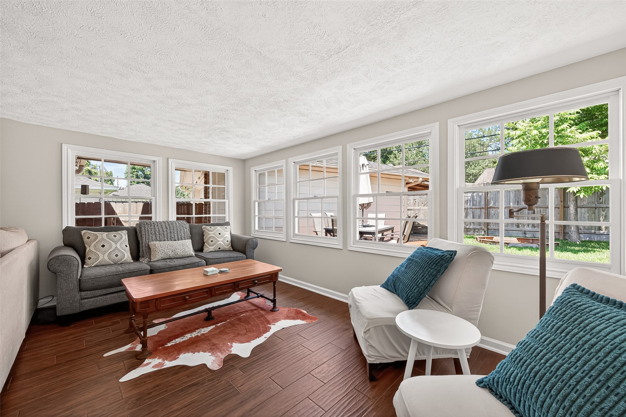 Still part of the family room, this cozy sunroom area features large windows for ample natural light, warm flooring, and comfortable seating, offering a relaxing view of the backyard.