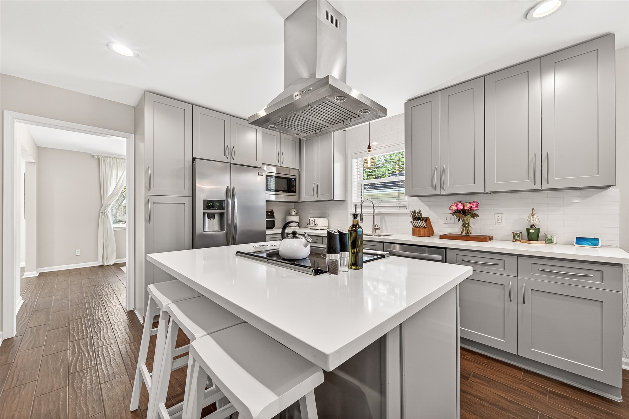 This modern kitchen features sleek gray cabinetry, stainless steel appliances, and a central island with bar seating.