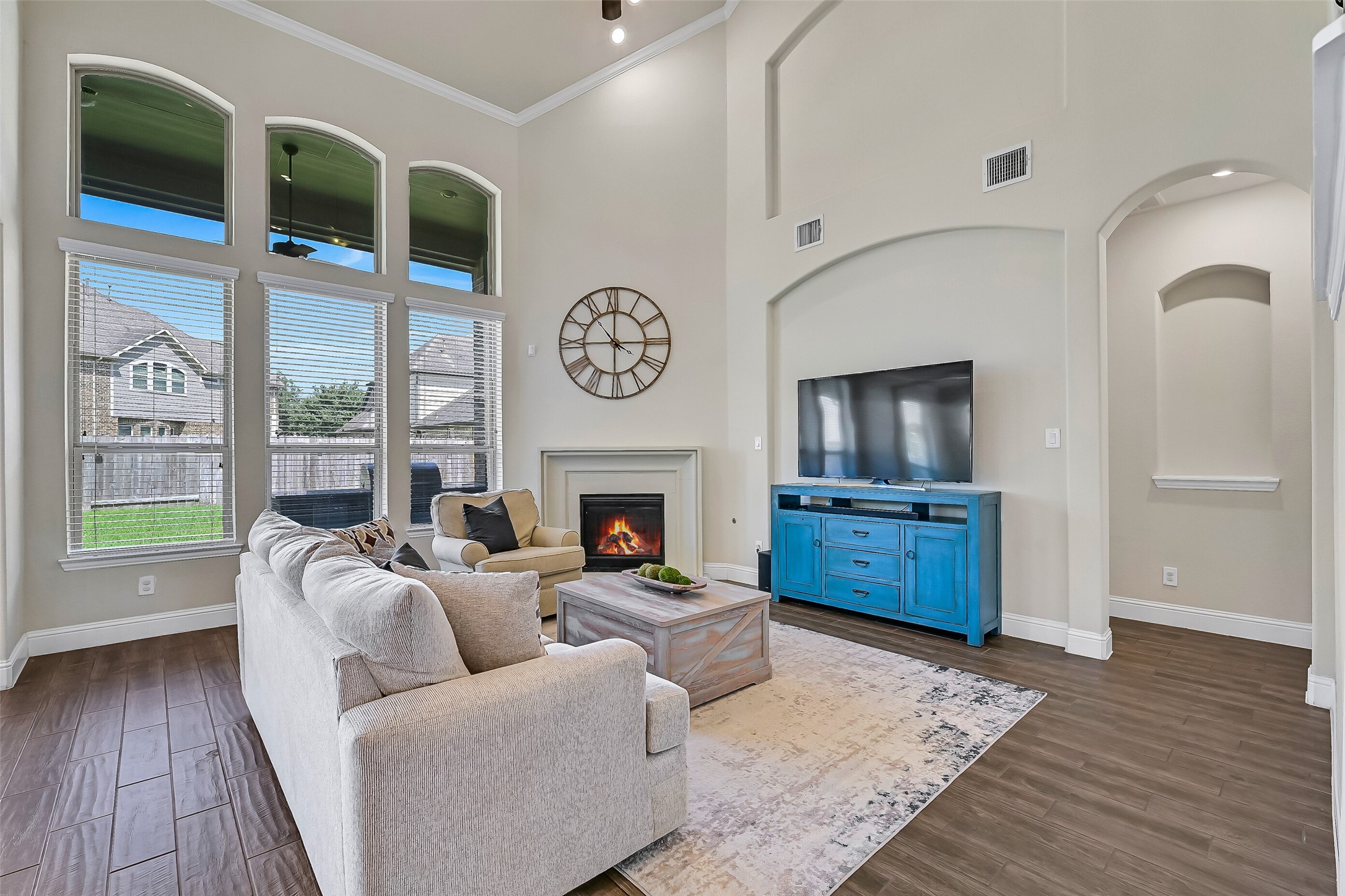 Natural light pours through towering windows, highlighting the home's soaring ceilings and spacious layout. Whether enjoying a cozy evening by the fireplace or gathering with friends and family, this inviting living space was designed to bring everyone together.