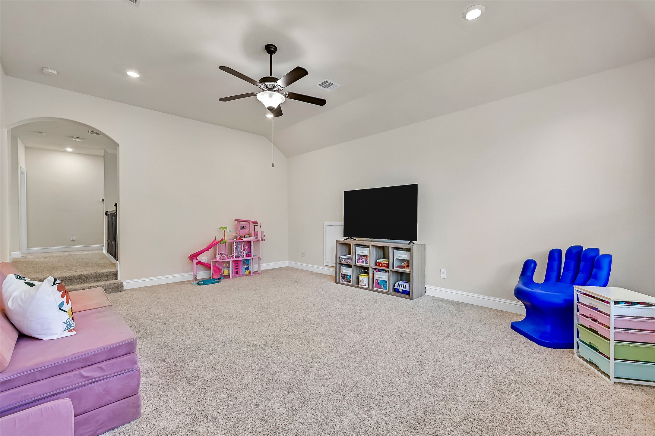 A spacious second-floor game room offers the perfect retreat for movie nights, gaming, a playroom, or a home fitness area. Plush carpeting, a vaulted ceiling, recessed lighting, a ceiling fan, and abundant natural light create a comfortable space everyone will enjoy.