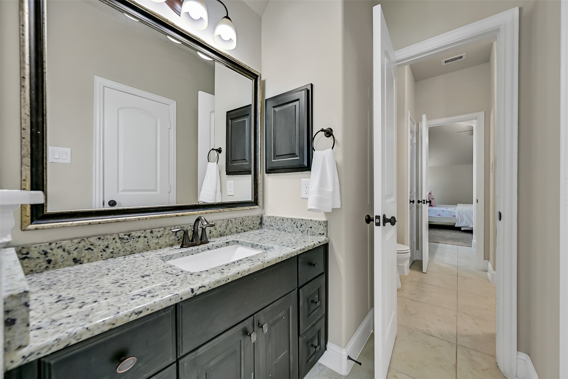 Connecting two generously sized secondary bedrooms, this well-appointed bath includes granite countertops, abundant storage, and a private tub and shower area tucked behind a separate doormaking busy mornings more efficient for everyone.