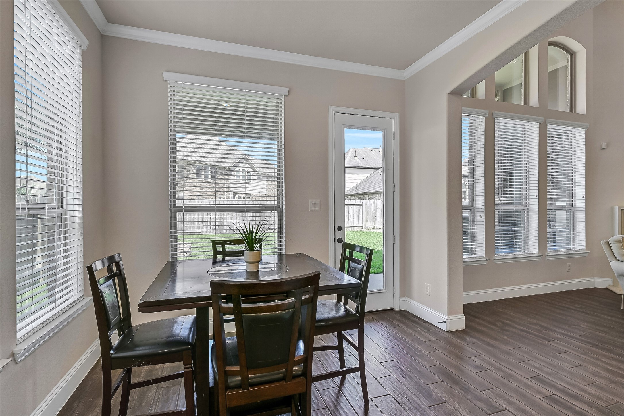 Natural light fills the breakfast area through windows overlooking the backyard, while an 8-foot glass door provides easy access to the covered patio. Whether enjoying your morning coffee or casual family meals, this inviting space offers peaceful backyard views.