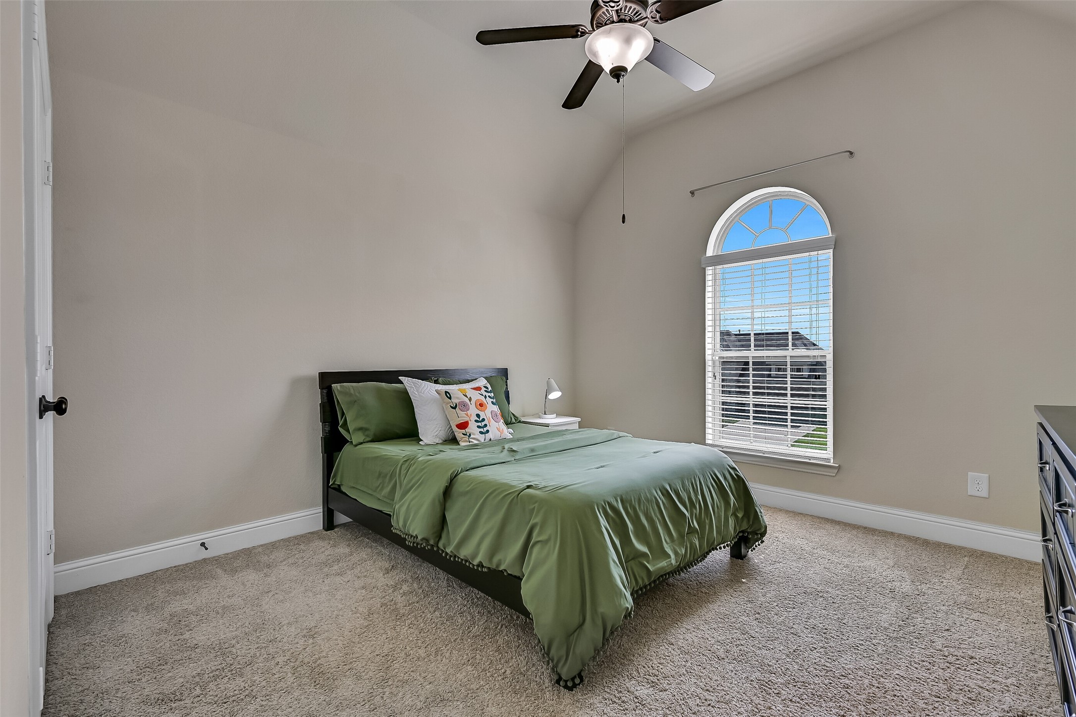 Just off the game room, this spacious secondary bedroom offers vaulted ceilings, plush carpeting, a lighted ceiling fan, and a charming arched window that fills the room with natural light. With its own nearby full bath, it provides comfort and privacy for family members or overnight guests.