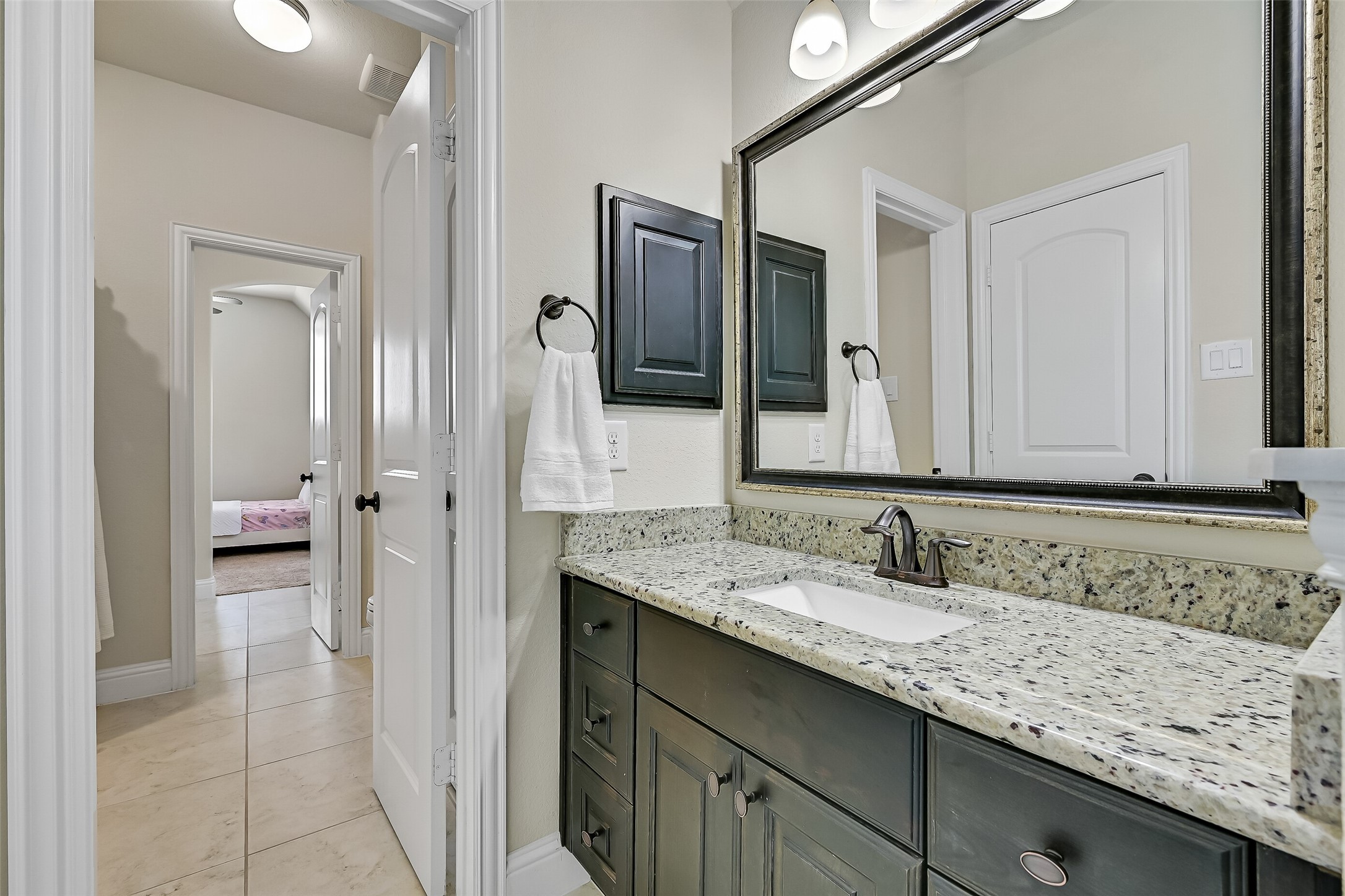 Designed for both convenience and privacy, the Jack-and-Jill bath features a granite vanity with an undermount sink, stained wood cabinetry, oil-rubbed bronze fixtures, and direct access from each adjoining bedroom. The thoughtful layout makes sharing easy while giving everyone their own space.