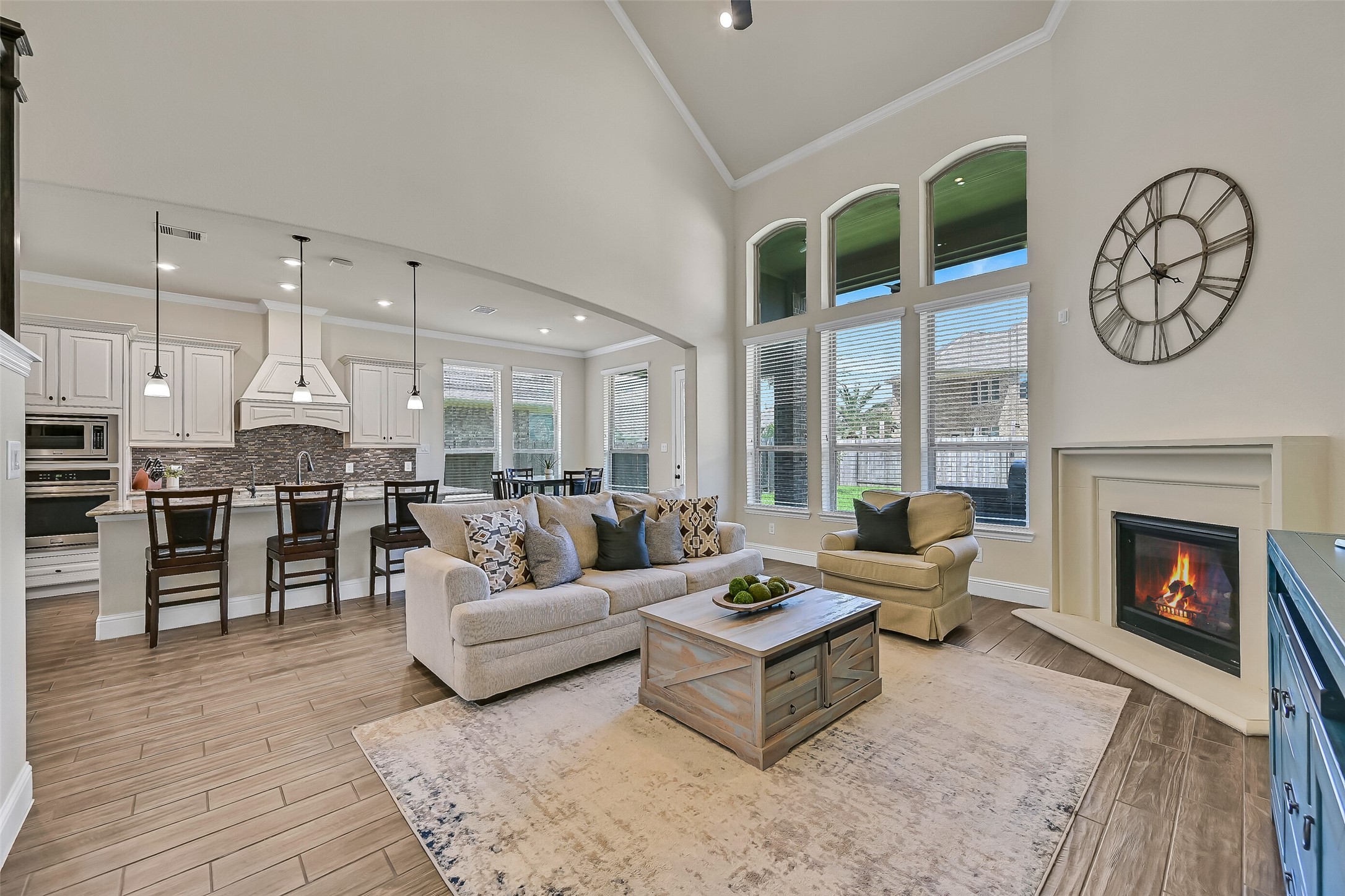 The heart of the home welcomes you with soaring 20-foot ceilings, a dramatic wall of windows that fills the space with natural light, and a cast stone gas log fireplace that creates a warm focal point. Wood-look tile flooring and an open layout seamlessly connect the family room to the kitchen and breakfast area.