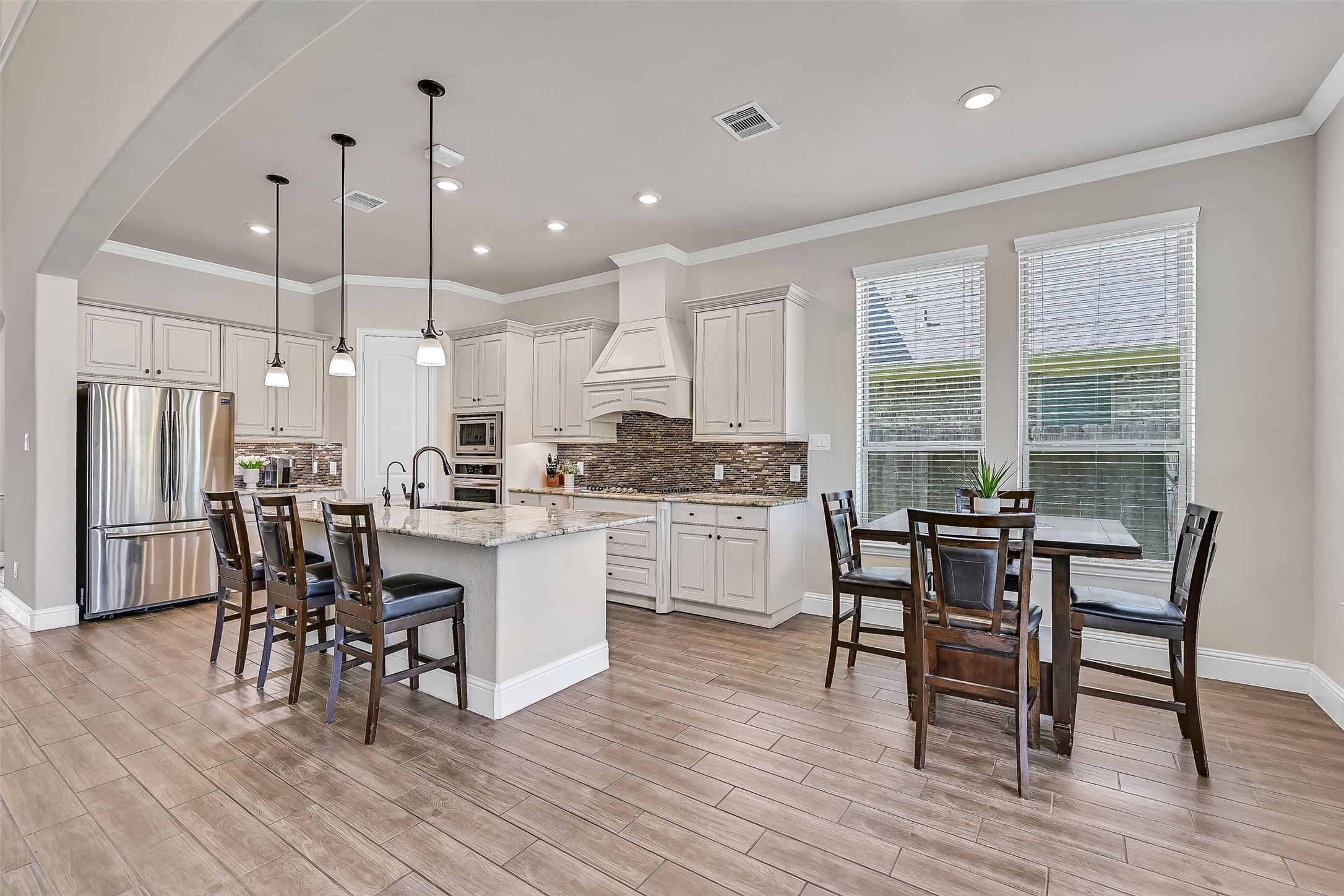 The spacious island kitchen is thoughtfully designed with seating for four, granite countertops, abundant cabinetry, and a seamless connection to the breakfast area. Pendant lighting, under-cabinet lighting, and windows overlooking the backyard create a bright, welcoming space for everyday living.