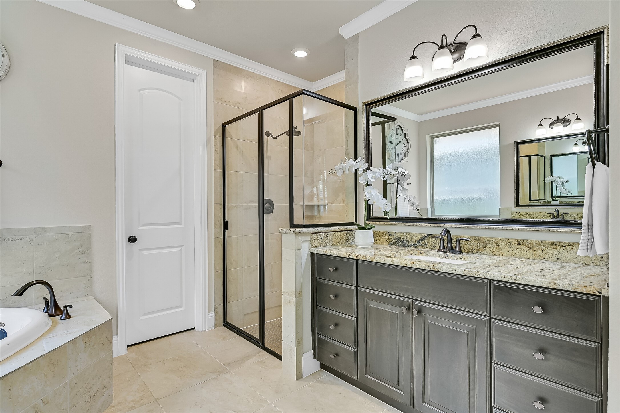 Start and end each day in a bathroom designed for comfort, featuring expansive granite countertops, abundant storage, elegant oil-rubbed bronze fixtures, and a spacious walk-in shower finished with timeless tile, a sleek glass enclosure, & a water softening system on the home.