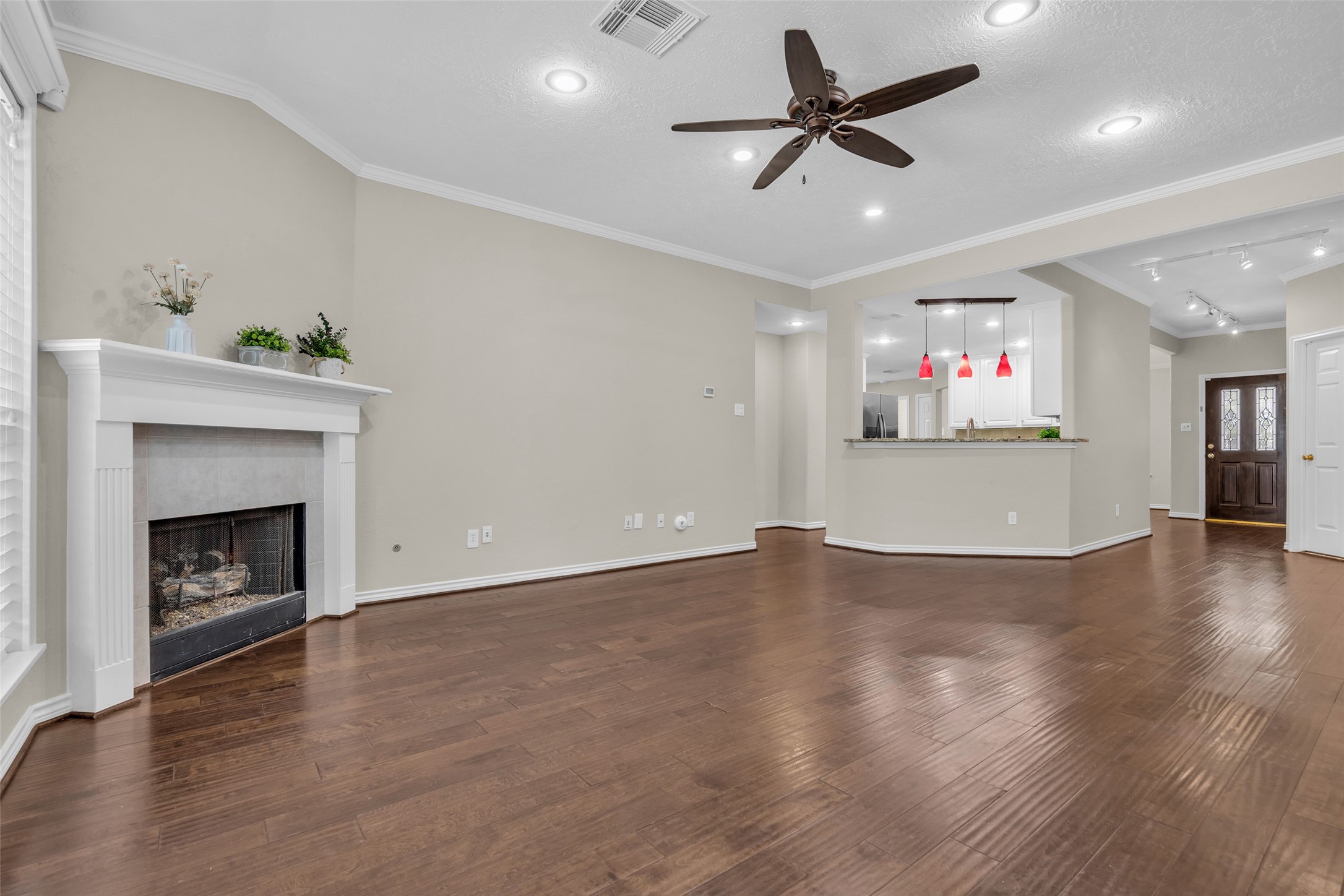 Living area offers hard flooring, gas fireplace, crown molding, neutral colors, and ample lighting.