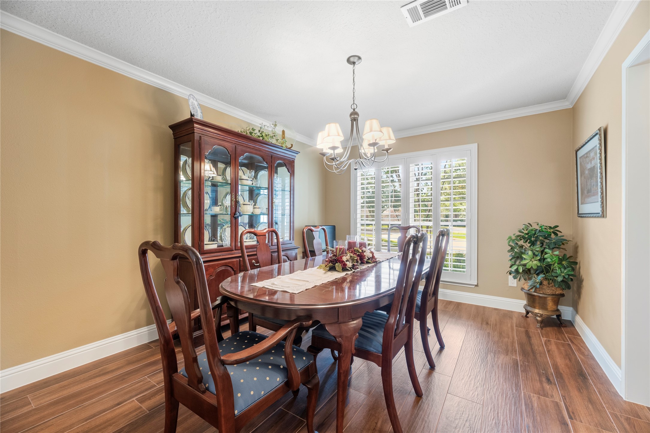The formal dining room with crown molding, window shutters and wood-look tile flooring.