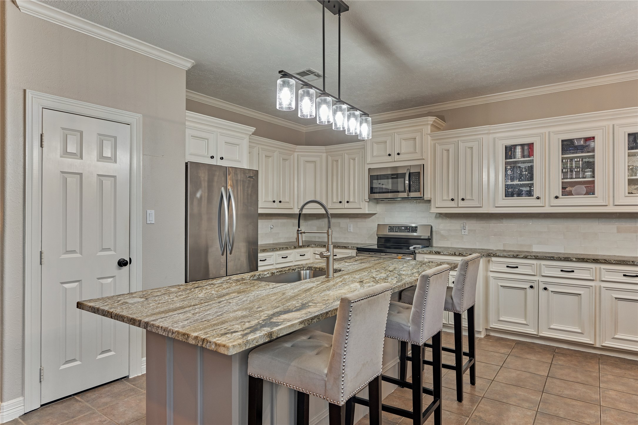 Stylish lighting highlights the expansive breakfast bar, offering generous seating and a warm, inviting space for casual dining and entertaining.