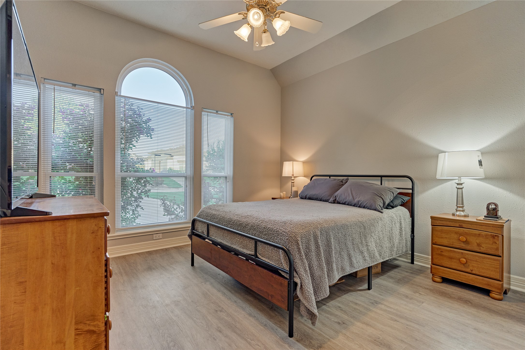 Secondary bedroom #1 features updated flooring, high ceilings, and a wall-of-windows that overlook the front yard and fills the space with abundant natural light.