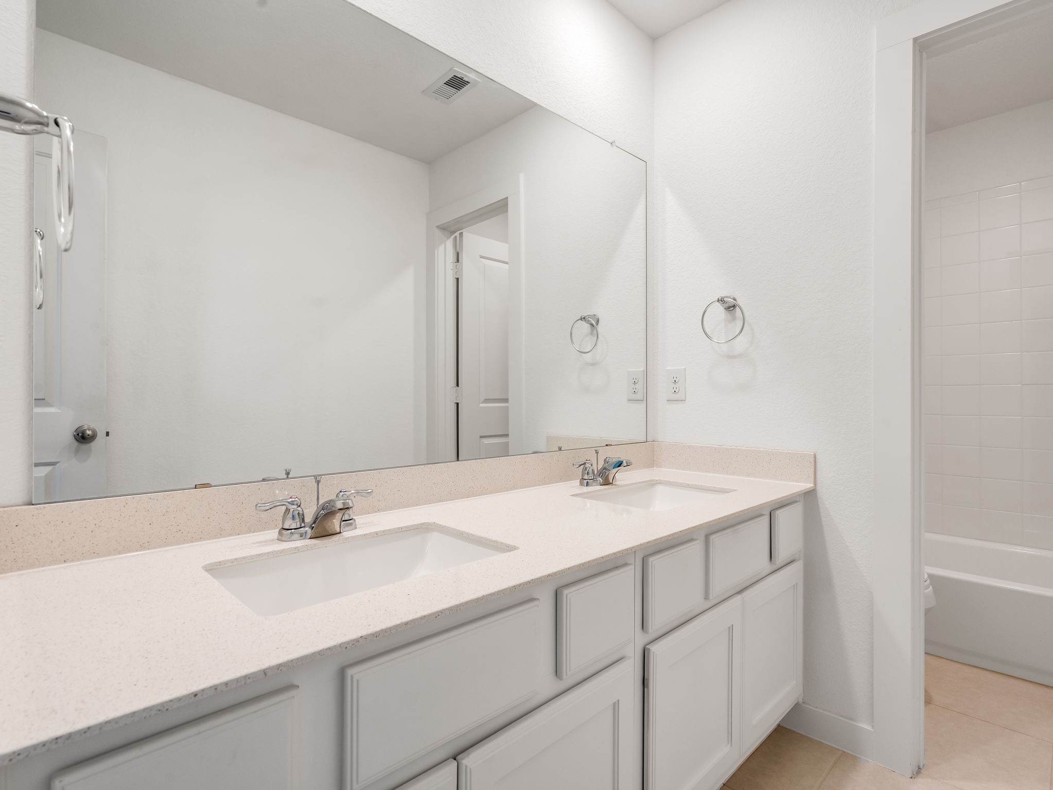 The bathroom vanity brings bright counters, clean cabinetry, and a simple mirror detail together. A crisp everyday bath finish. Virtually staged.