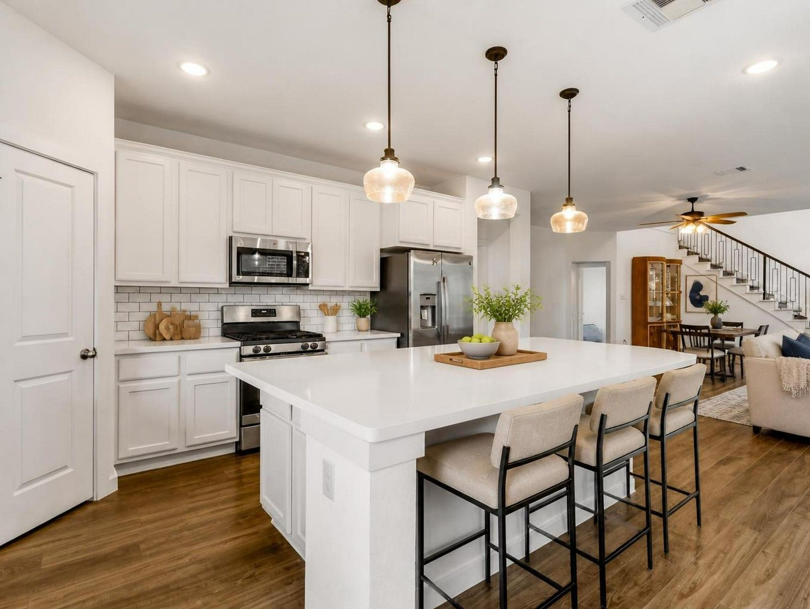 The kitchen brings together quartz counters, a large island, stainless appliances, and pendant lighting. A bright central space with a luxury everyday feel. Virtually staged.