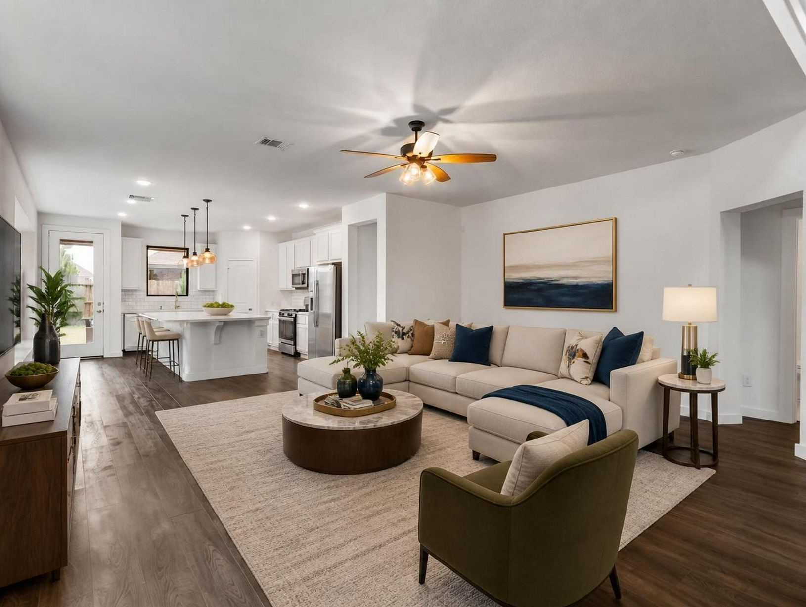 The living room flows directly into the kitchen, creating one open and connected main level. Warm floors and natural light give the space a composed feel. Virtually staged.