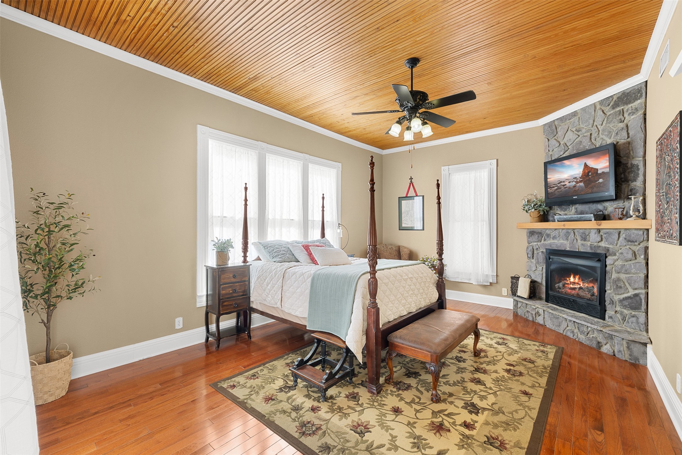 The first-floor primary bedroom is a serene retreat with warm wood floors, a beadboard ceiling and its own fireplace.